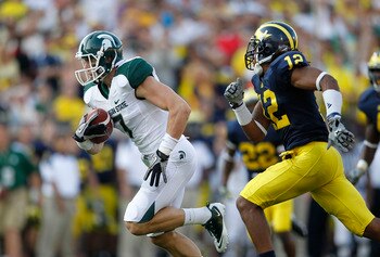ANN ARBOR, MI - OCTOBER 09:  Steve Nichol #7 of the Michigan State Spartans runs past J. T. Floyd #12 of the Michigan Wolverines after catching a 42 yard pass compleation from Kirk Cousins #8 during the third quarter of the game against the Michigan Wolve