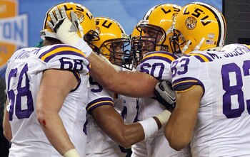ARLINGTON, TX - JANUARY 07:  (L-R) Josh Dworaczyk #68, Jordan Jefferson #9, Will Blackwell #60 and Mitch Joseph #83 of the LSU Tigers celebrate a touchdown against the Texas A&M Aggies during the AT&T Cotton Bowl at Cowboys Stadium on January 7, 2011 in A