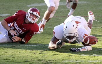 DALLAS - OCTOBER 02:  Quarterback Landry Jones #12 of the Oklahoma Sooners fumbles the ball out of play in front of Jared Norton #11 of the Texas Longhorns in the fourth quarter at the Cotton Bowl on October 2, 2010 in Dallas, Texas.  (Photo by Ronald Mar