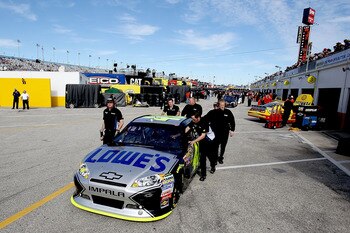 DAYTONA BEACH, FL - FEBRUARY 12:  Crew members push the car of Jimmie Johnson, driver of the #48 Lowe's Chevrolet, through the garage area during practice for the NASCAR Sprint Cup Series Daytona 500 at Daytona International Speedway on February 12, 2011 