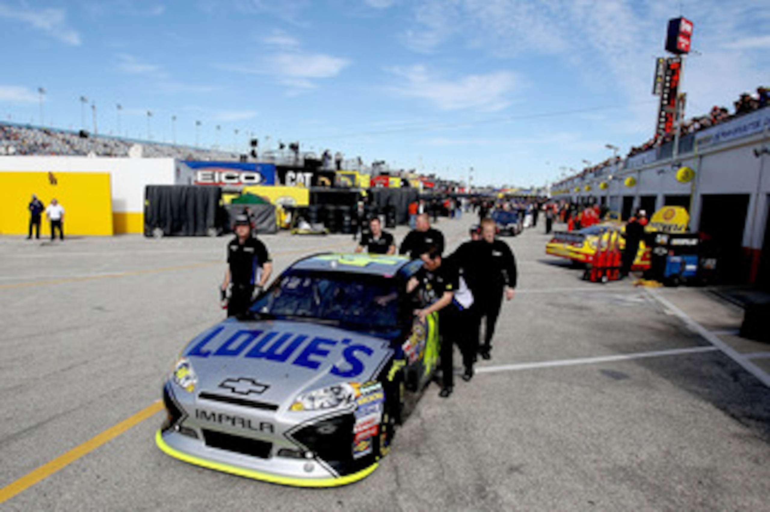 DAYTONA BEACH, FL - FEBRUARY 12:  Crew members push the car of Jimmie Johnson, driver of the #48 Lowe's Chevrolet, through the garage area during practice for the NASCAR Sprint Cup Series Daytona 500 at Daytona International Speedway on February 12, 2011 