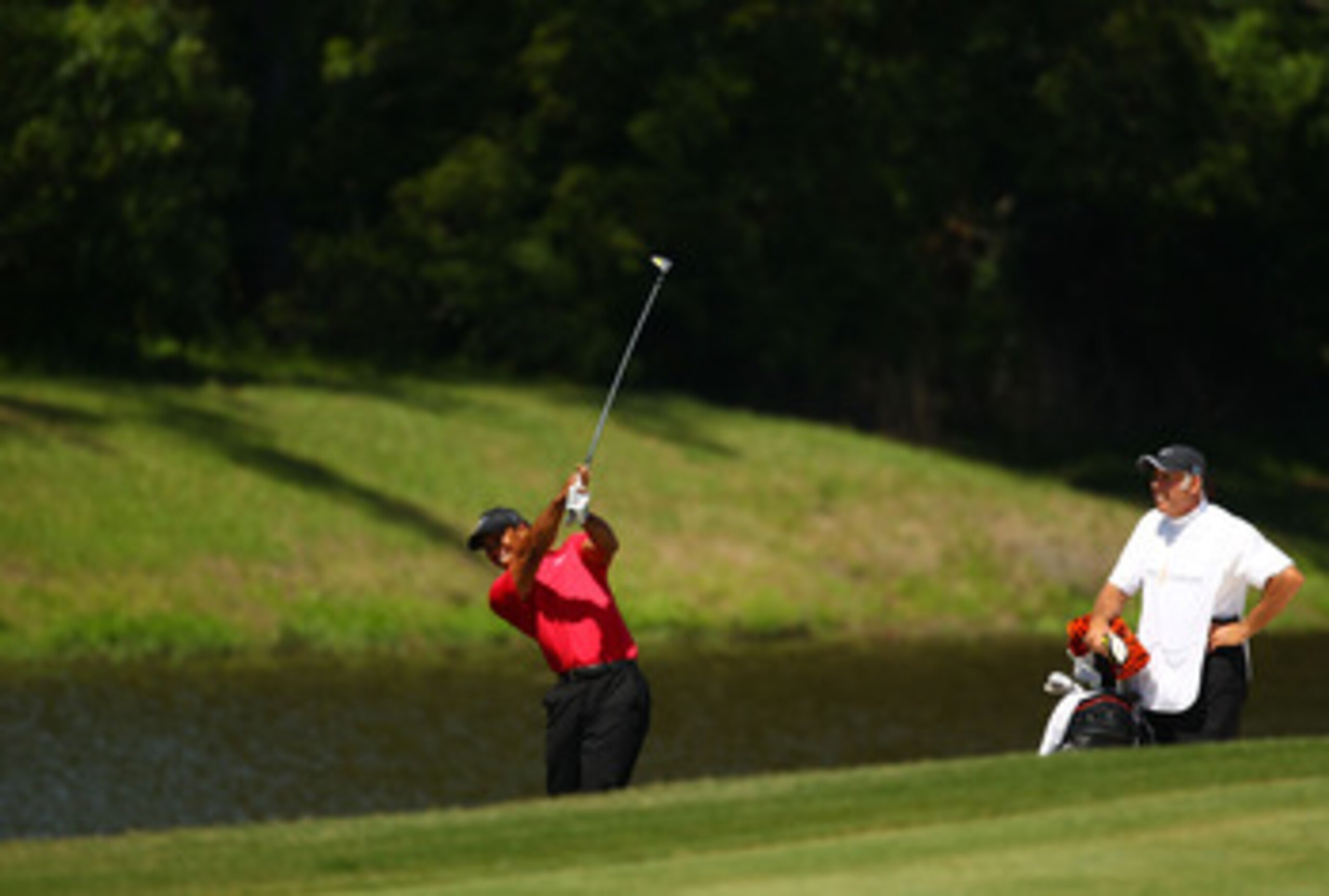 PONTE VEDRA BEACH, FL - MAY 09:  Tiger Woods plays his third shot on the fifth hole as caddie Steve Williams looks on during the final round of THE PLAYERS Championship held at THE PLAYERS Stadium course at TPC Sawgrass on May 9, 2010 in Ponte Vedra Beach