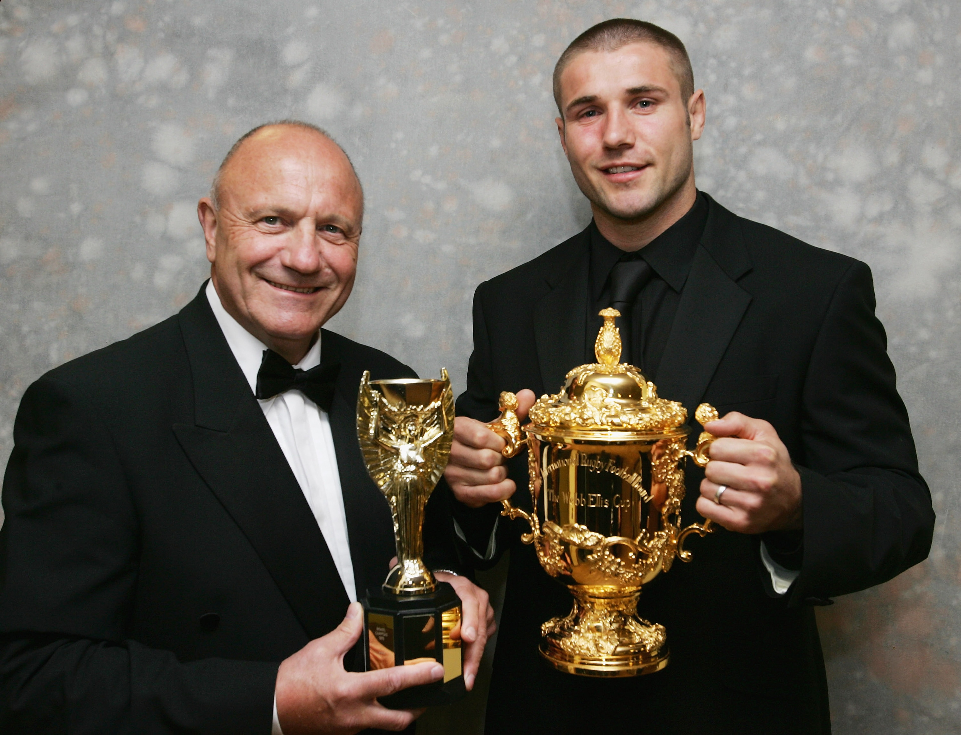 NORTHAMPTON, UNITED KINGDOM - MAY 3: George Cohen (L) poses with a replica of the Jules Rimet Trophy (which he won in 1966 as part of the England World Cup winning footbal team) and his nephew Ben Cohen, holding the Webb Ellis Trophy (which he won as pa NORTHAMPTON, UNITED KINGDOM - MAY 3: George Cohen (L) poses with a replica of the Jules Rimet Trophy (which he won in 1966 as part of the England World Cup winning footbal team) and his nephew Ben Cohen, holding the Webb Ellis Trophy (which he won as pa