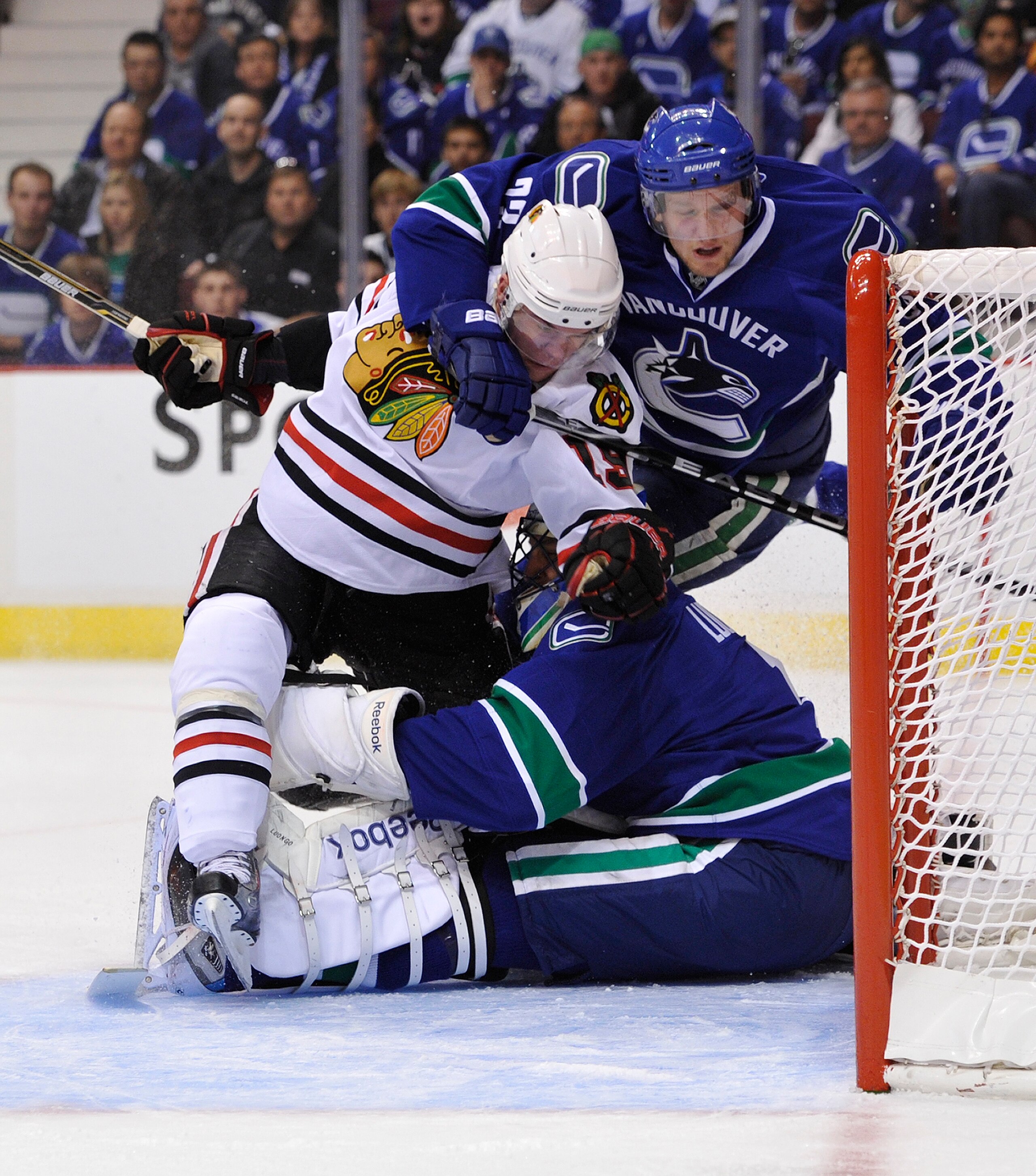 VANCOUVER, CANADA - APRIL 21: Jonathan Toews #19 of the Chicago Blackhawks reacts in front of goalie Roberto Luongo #1 of the Vancouver Canucks while being hauled down by Alexander Edler #23 of the Vancouver Canucks during the first period in Game Five of VANCOUVER, CANADA - APRIL 21: Jonathan Toews #19 of the Chicago Blackhawks reacts in front of goalie Roberto Luongo #1 of the Vancouver Canucks while being hauled down by Alexander Edler #23 of the Vancouver Canucks during the first period in Game Five of