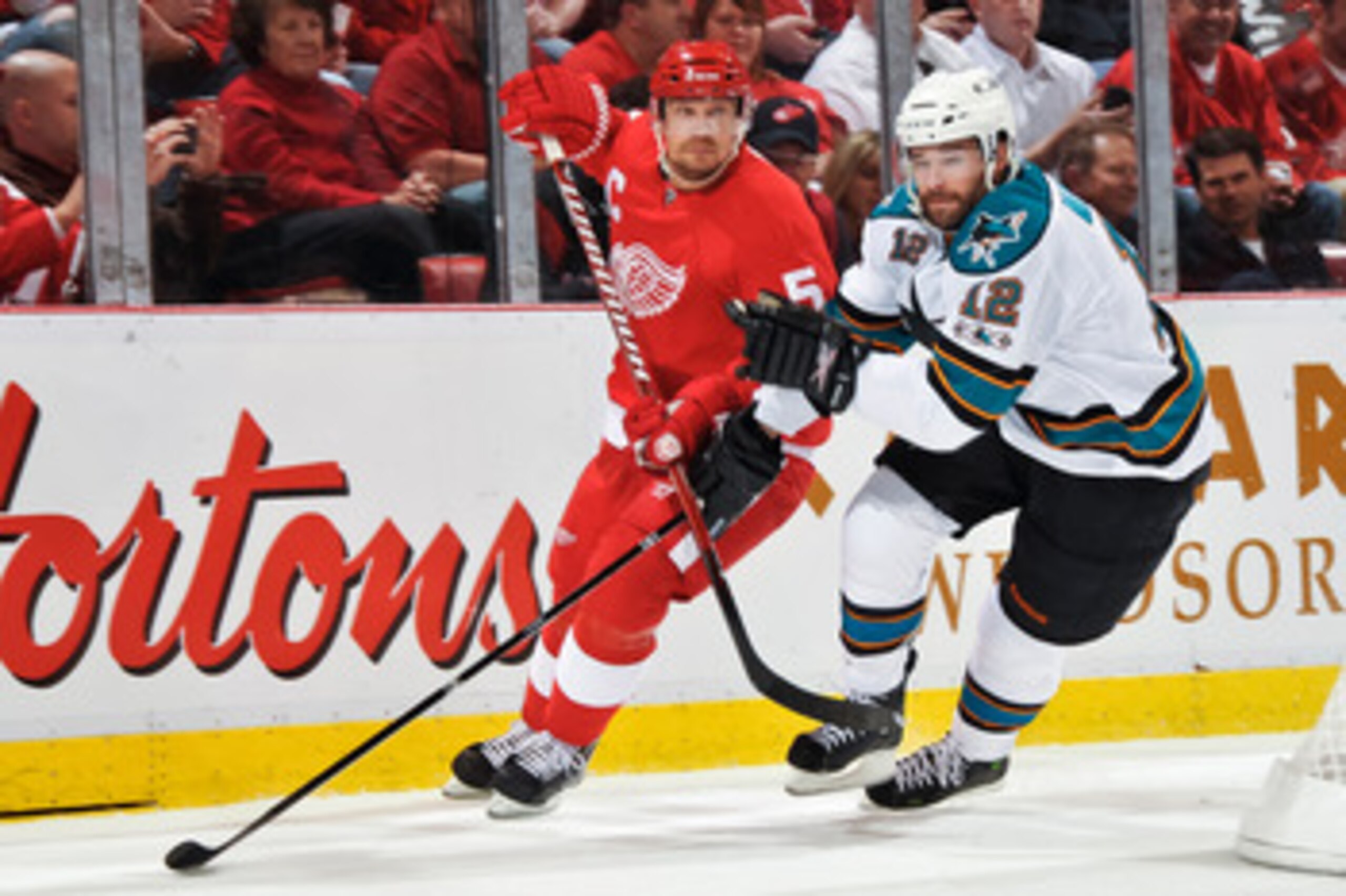DETROIT - MAY 4: Nicklas Lidstrom #5 of the Detroit Red Wings and Patrick Marleau #12 of the San Jose Sharks skate after a loose puck in Game Three of the Western Conference Semifinals during the 2011 NHL Stanley Cup Playoffs on May 4, 2011 at Joe Louis A