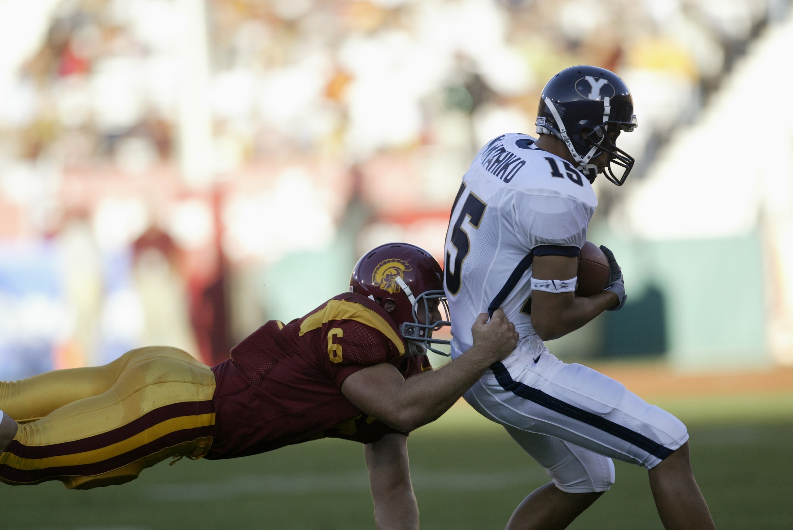 LOS ANGELES - SEPTEMBER 6:  Receiver Jason Kukahiko #15 of the BYU Cougars is brought down after a catch by linebacker Matt Grootegoed #6 of the USC Trojans on September 6, 2003 at the Los Angeles Coliseum in Los Angeles, California.  USC defeated BYU 35-