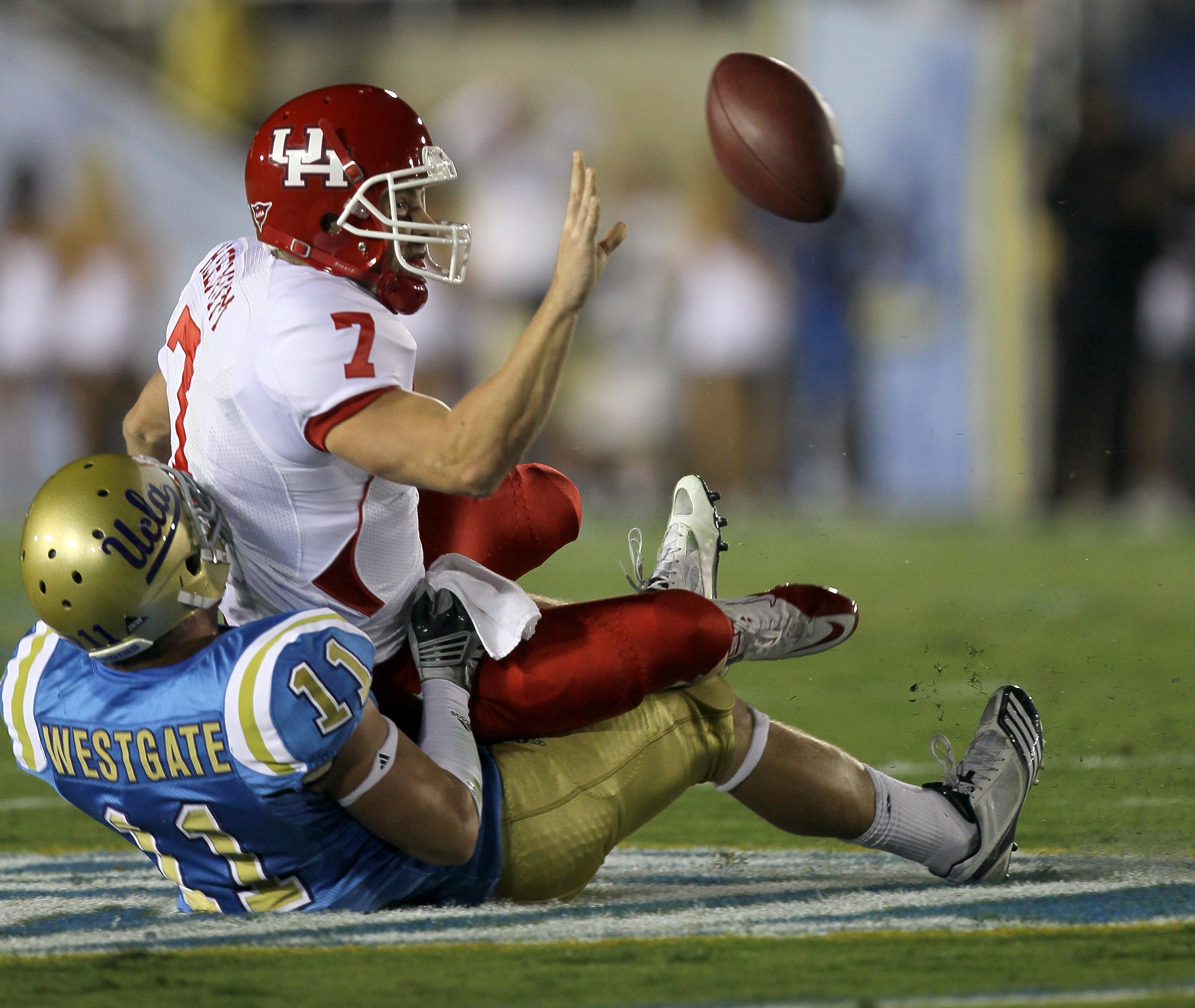 PASADENA, CA - SEPTEMBER 18:  Quarterback Case Keenum #7 of the Houston Cougars manages to dump off a pass as he is pulled down by linebacker Sean Westgate #11 of the UCLA Bruins at the Rose Bowl on September 18, 2010 in Pasadena, California.  (Photo by S