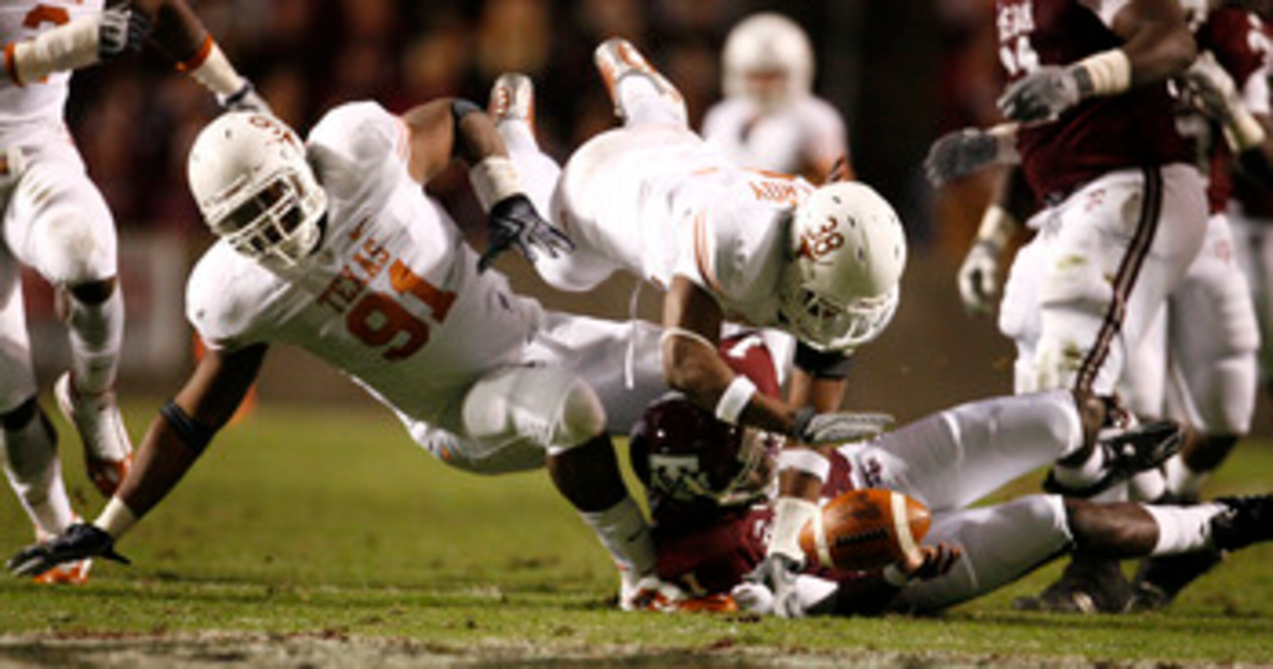COLLEGE STATION, TX - NOVEMBER 26: Quarterback Jerrod Johnson #1 of the Texas A&M Aggies loses control of the ball as defensive tackle Kheeston Randall #91 and linebacker Roddrick Muckelroy #38 of the Texas Longhorns go for the loose ball in the first hal COLLEGE STATION, TX - NOVEMBER 26: Quarterback Jerrod Johnson #1 of the Texas A&M Aggies loses control of the ball as defensive tackle Kheeston Randall #91 and linebacker Roddrick Muckelroy #38 of the Texas Longhorns go for the loose ball in the first hal
