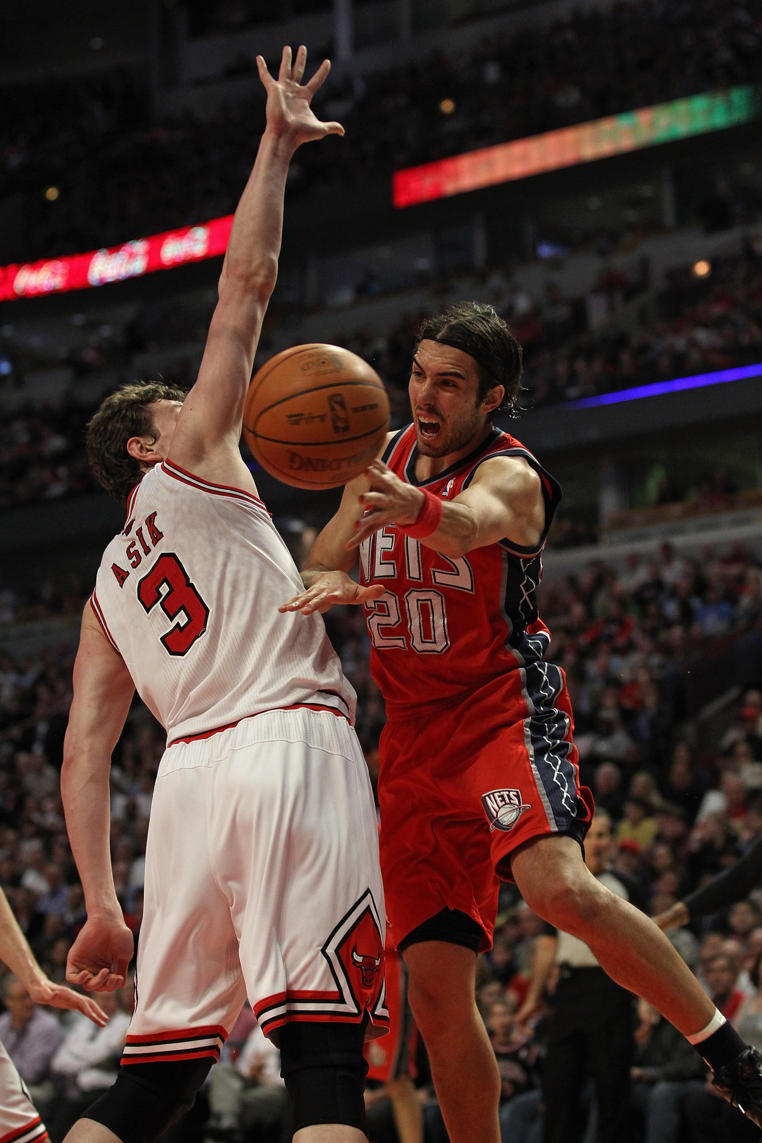 CHICAGO, IL - APRIL 13: Sasha Vujacic #20 of the New Jersey Nets passes the ball around Omer Asik #3 of the Chicago Bulls at United Center on April 13, 2011 in Chicago, Illinois. NOTE TO USER: User expressly acknowledges and agrees that, by downloading an