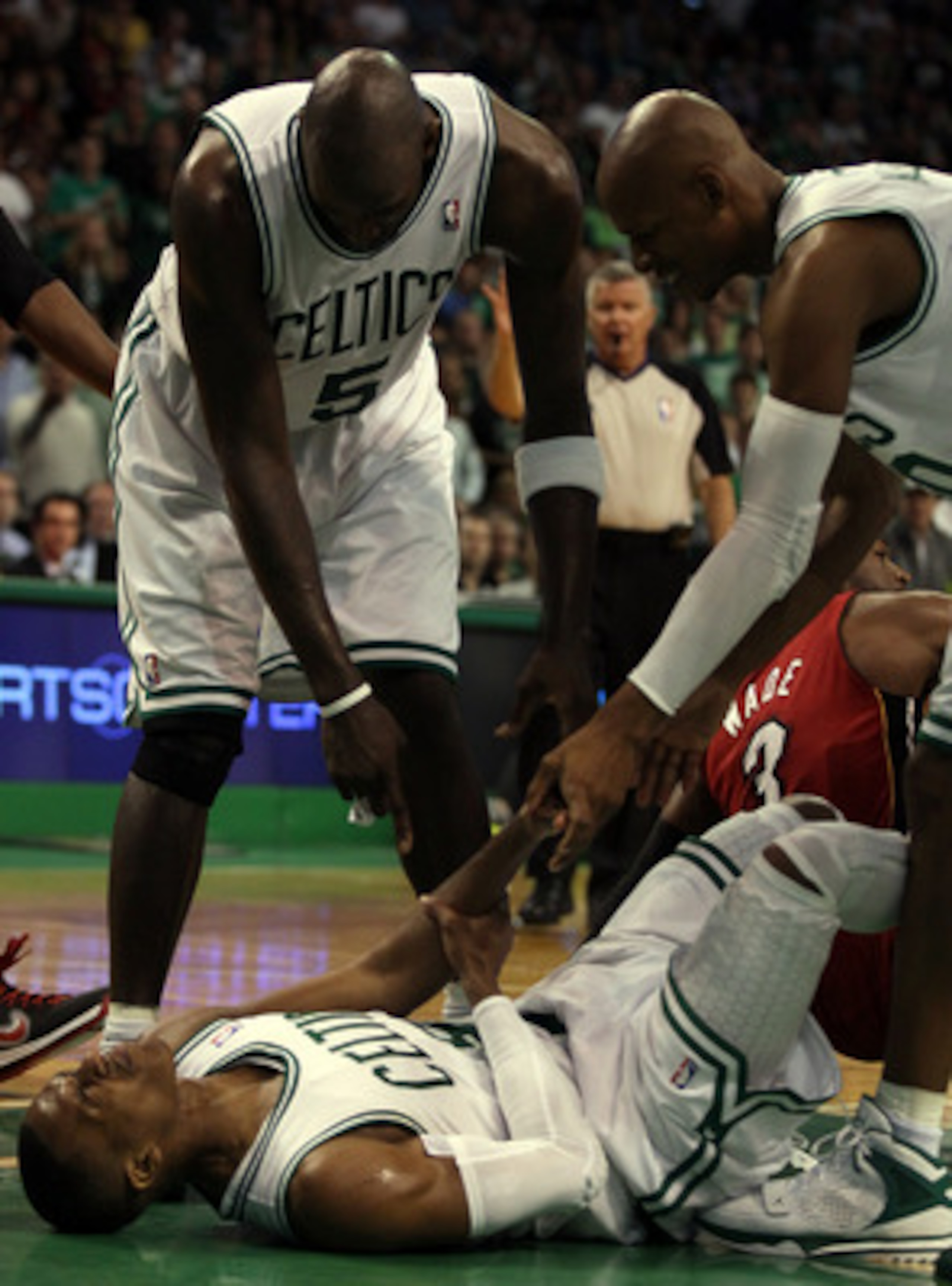 BOSTON, MA - MAY 07:  Kevin Garnett #3 and Ray Allen #20 try to help up teammate Rajon Rondo #9 of the Boston Celtics after he is knocked down by Dwyane Wade #3 of the Miami Heat in Game Three of the Eastern Conference Semifinals in the 2011 NBA Playoffs 