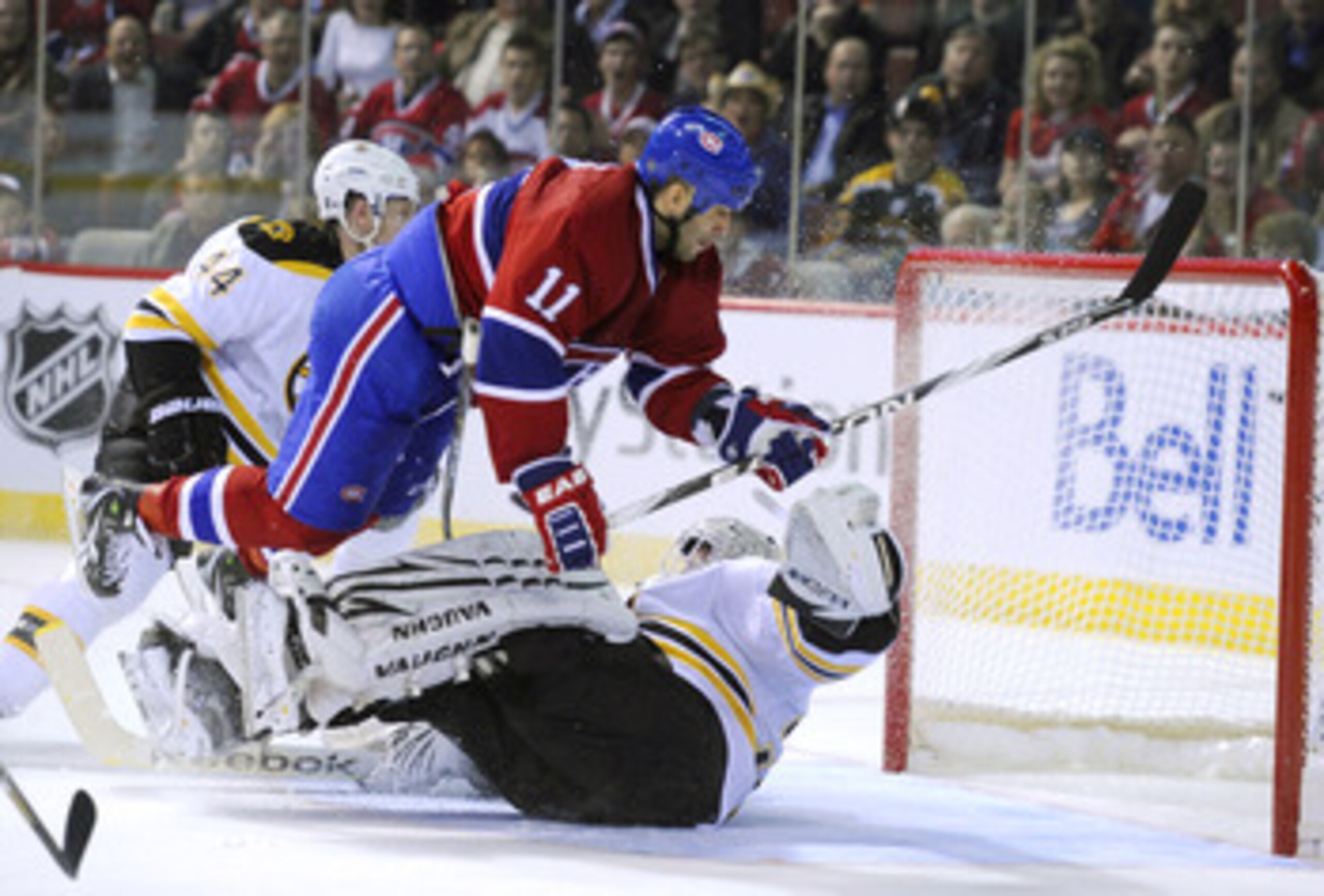 MONTREAL, CANADA - APRIL 26:  Scott Gomez #11 of the Montreal Canadiens goes airborne over a sprawled out Tim Thomas #30 of the Boston Bruins in Game Six of the Eastern Conference Quarterfinals during the 2011 NHL Stanley Cup Playoffs at the Bell Centre o
