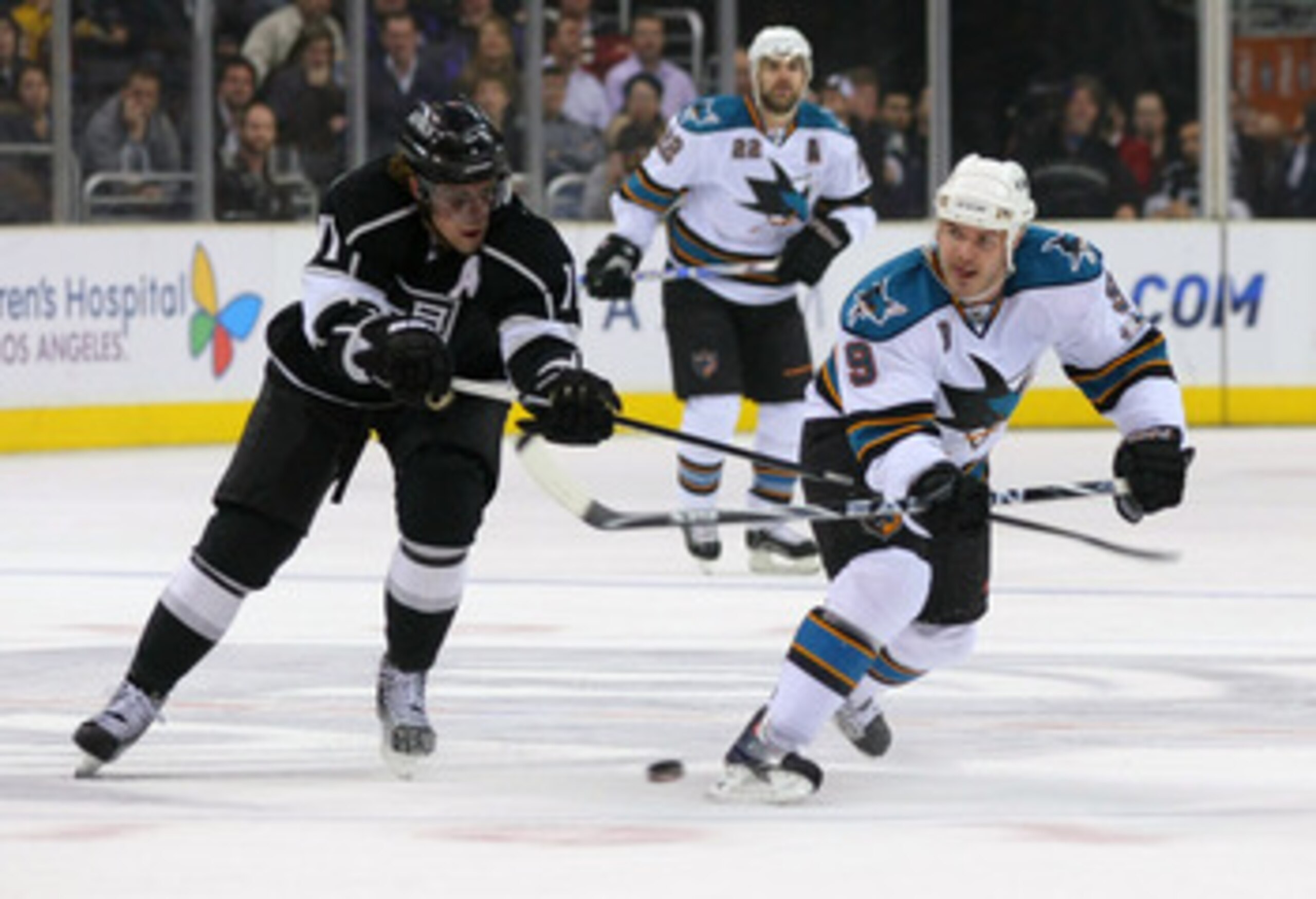 LOS ANGELES, CA - MARCH 24:  Ian White #9 of the San Jose Sharks backhands the puck into the offensive zone under pressure from Anze Kopitar #11 of the Los Angeles Kings in the first period during the NHL game at Staples Center on March 24, 2011 in Los An