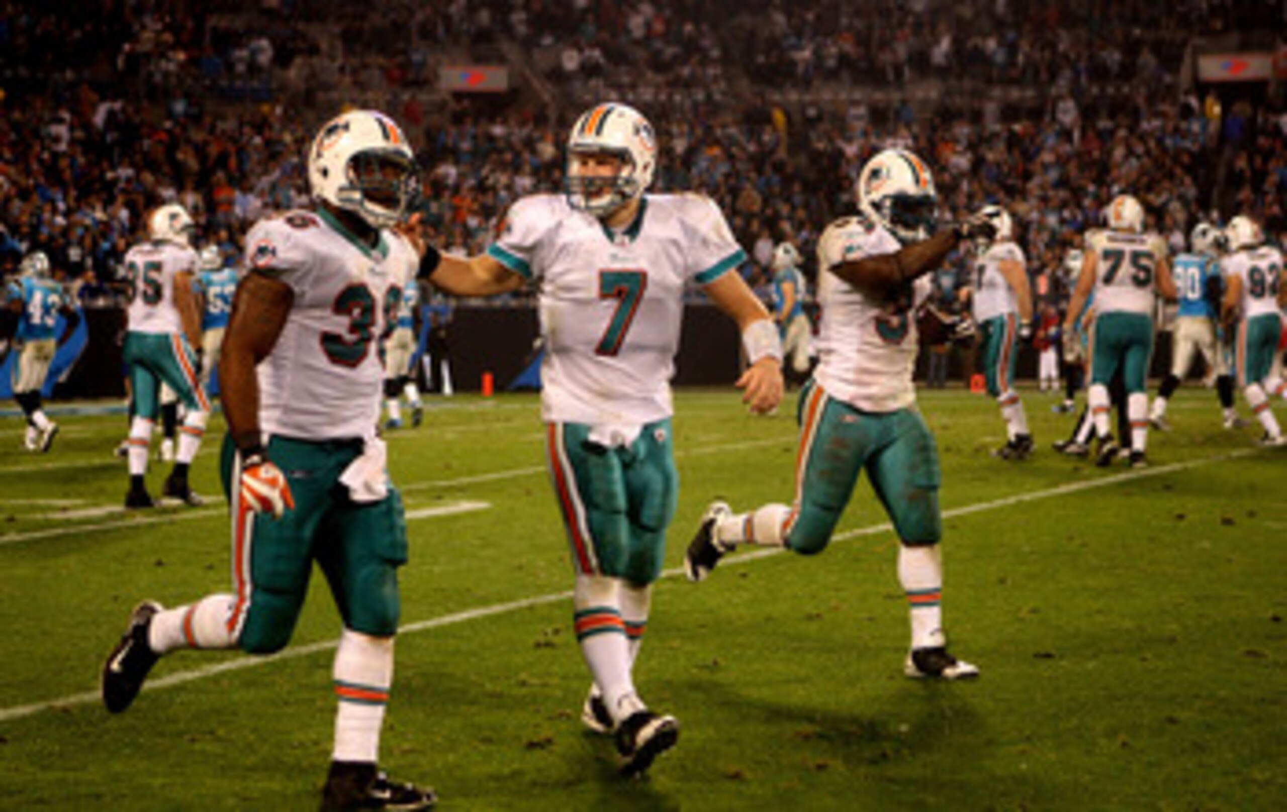 CHARLOTTE, NC - NOVEMBER 19:  Chad Henne #7 and teammates Lousaka Polite #36 and Ricky Williams #34 of the Miami Dolphins celebrate as they run off the field after a touchdown against the Carolina Panthers during their game at Bank of America Stadium on N