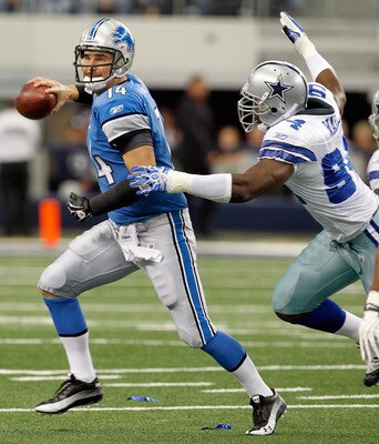 ARLINGTON, TX - NOVEMBER 21:  Quarterback Shaun Hill #14 of the Detroit Lions scrambles with the ball under pressure by Demarcus Ware #94 of the Dallas Cowboys at Cowboys Stadium on November 21, 2010 in Arlington, Texas.  The Cowboys beat the Lions 35-19.