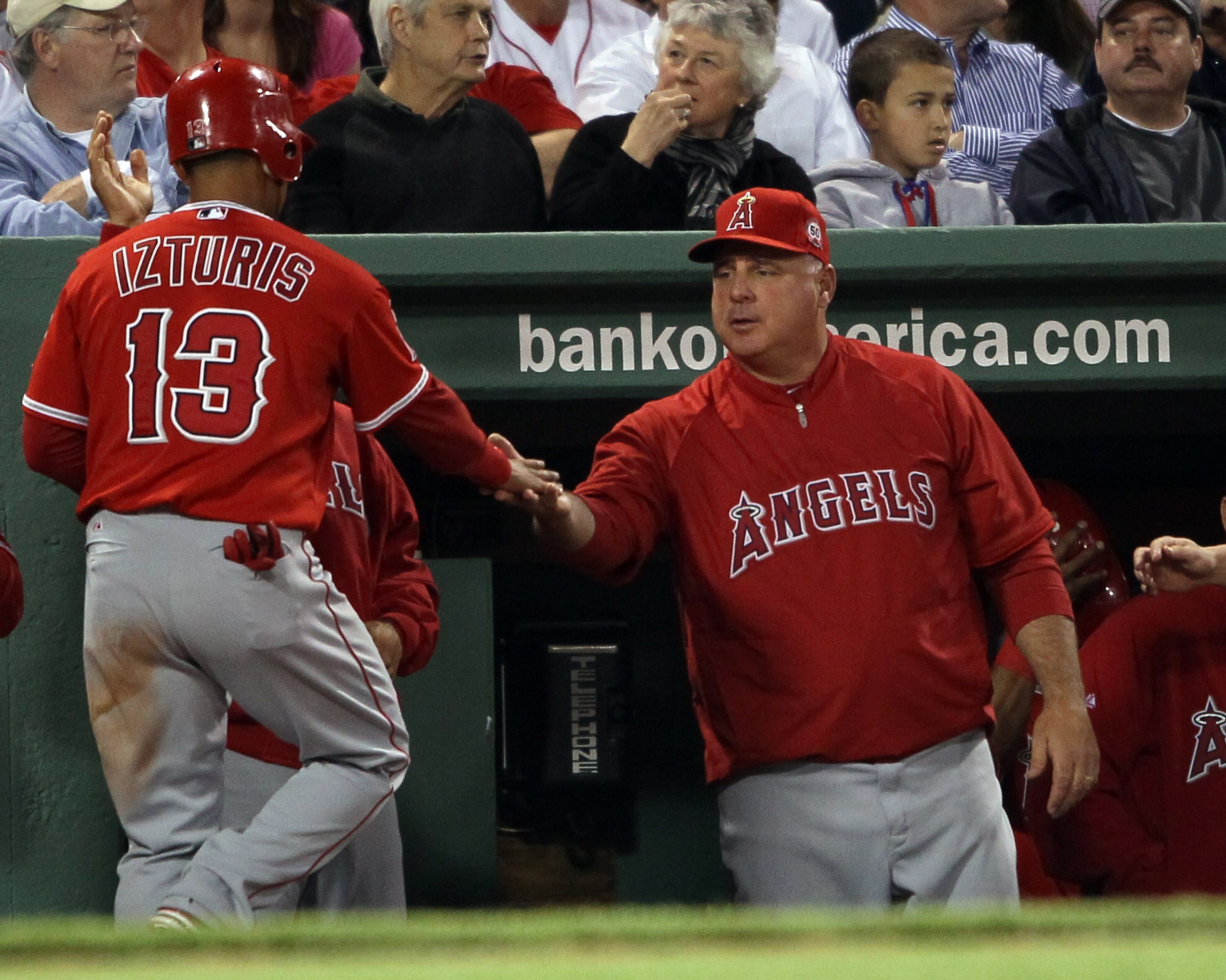 BOSTON, MA - MAY 02:  Maicer Izturis #13 of the Los Angeles Angels is congratulated by manager Mike Scioscia #14 after Izturis scored in the third inning against the Boston Red Sox on May 2, 2011 at Fenway Park in Boston, Massachusetts.  (Photo by Elsa/Ge