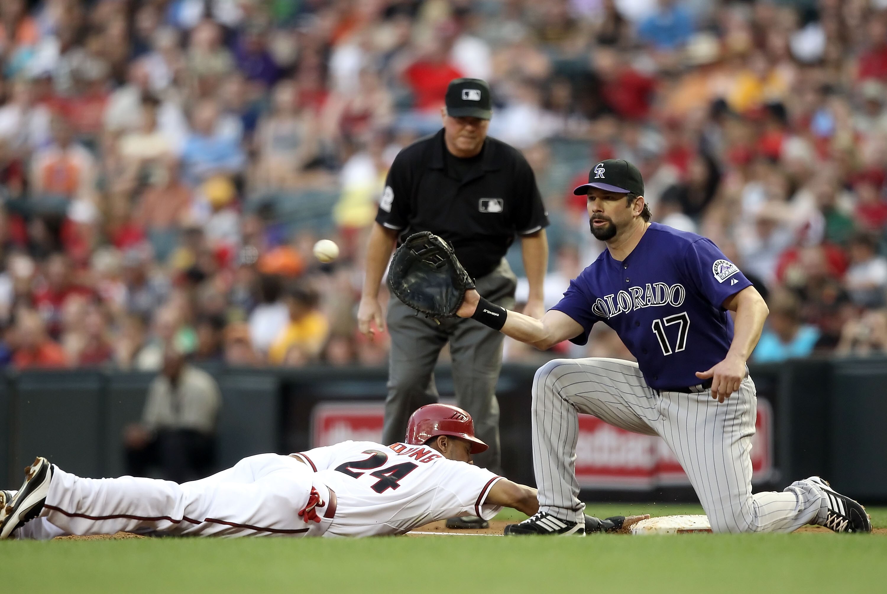 PHOENIX, AZ - MAY 05:  Chris Young #24 of the Arizona Diamondbacks safely dives back into first base ahead of infielder Todd Helton #17 of the Colorado Rockies during the Major League Baseball game at Chase Field on May 5, 2011 in Phoenix, Arizona.  (Phot