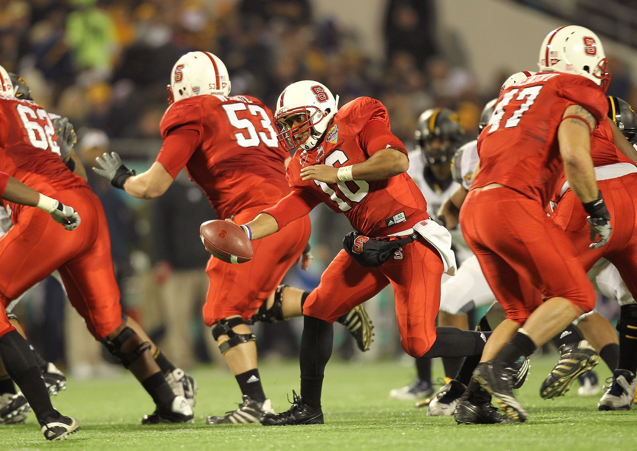 ORLANDO, FL - DECEMBER 28:  Russell Wilson #16 of the North Carolina State Wolfpack hands the ball off during the Champs Sports Bowl against the West Virginia Mountineers at Florida Citrus Bowl Stadium on December 28, 2010 in Orlando, Florida.  (Photo by