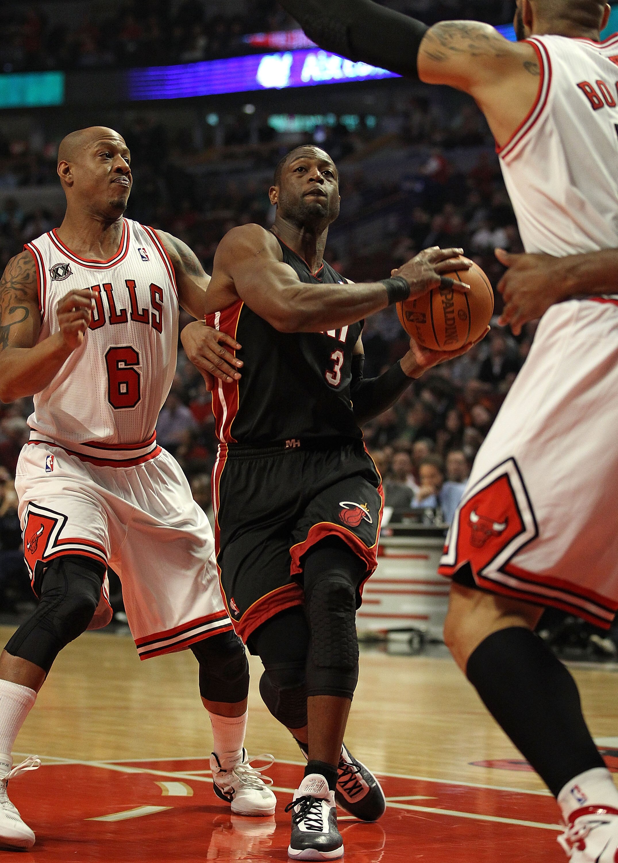 CHICAGO, IL - FEBRUARY 24: Dwyane Wade #3 of the Miami Heat drives to the basket between Keith Bogans #6 and Carlos Boozer #5 of the Chicago Bulls at the United Center on February 24, 2011 in Chicago, Illinois. The Bulls defeated the Heat 93-89. NOTE TO U