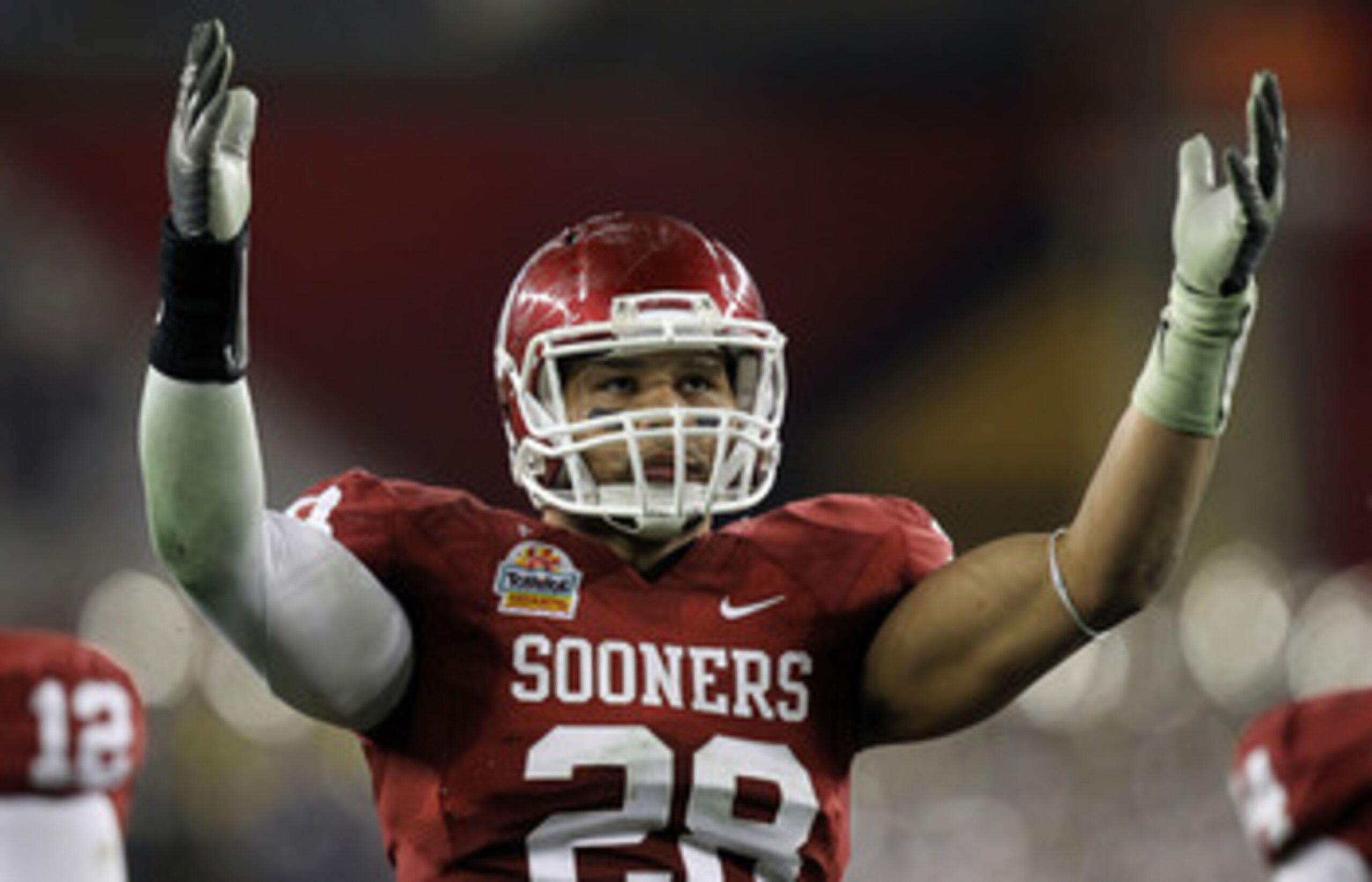 ARLINGTON, TX - DECEMBER 04:  Quarterback Landry Jones #12 of the Oklahoms Sooners slides to the turf after scrambling for a gain against Linebacker Lavonte David #4 of the Nebraska Cornhuskers at Cowboys Stadium on December 4, 2010 in Arlington, Texas.  