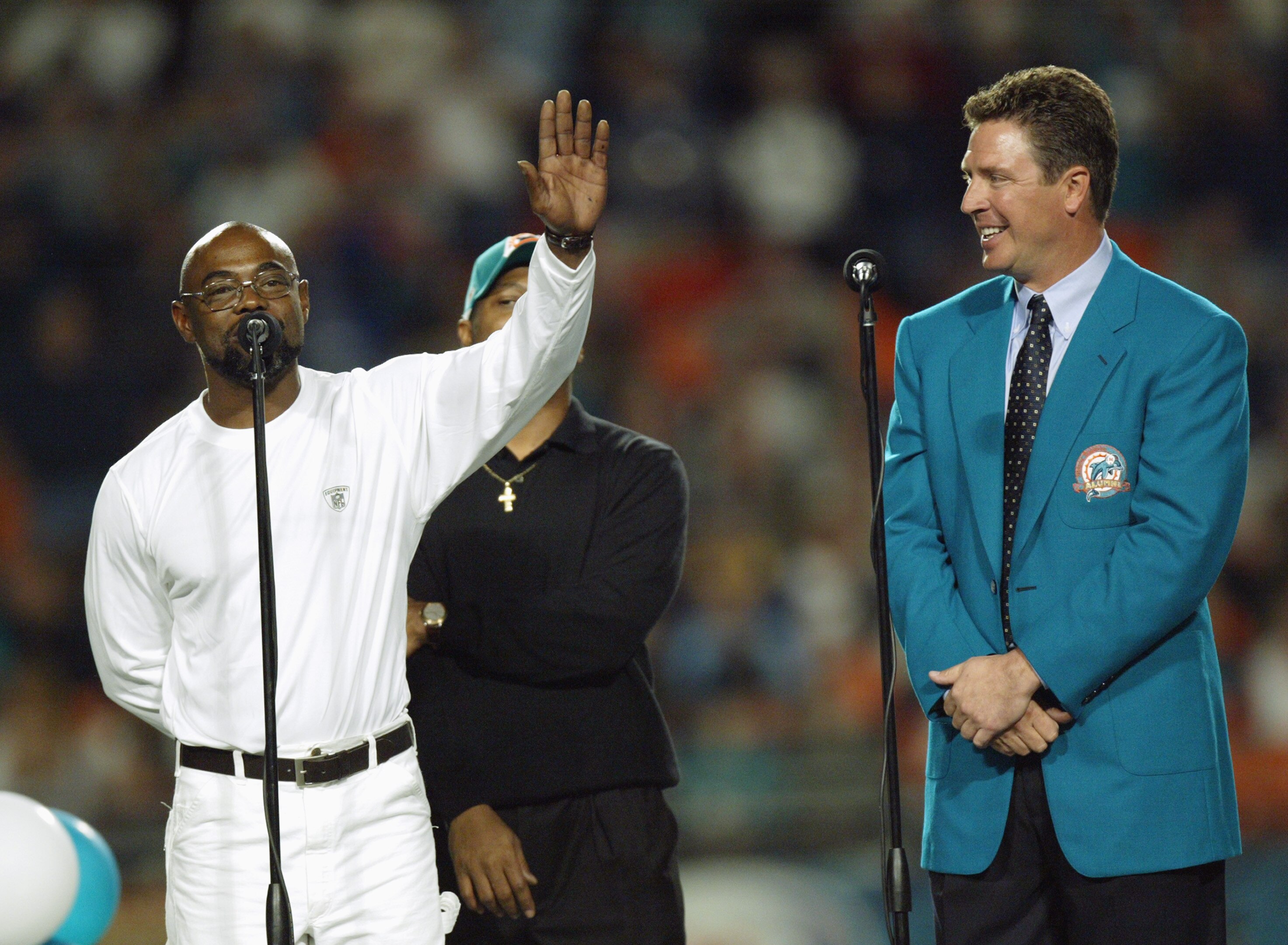 MIAMI - DECEMBER 15:  Former Miami Dolphins player Mark Duper speaks while waving to the crowd as former quarterback Dan Marino watches after Duper and teammate Mark Clayton, obscured were inducted into the Miami Dolphins Hall of Fame during half time of