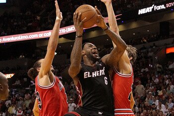 CHICAGO, IL - FEBRUARY 24: Dwyane Wade #3 of the Miami Heat drives to the basket between Keith Bogans #6 and Carlos Boozer #5 of the Chicago Bulls at the United Center on February 24, 2011 in Chicago, Illinois. The Bulls defeated the Heat 93-89. NOTE TO U