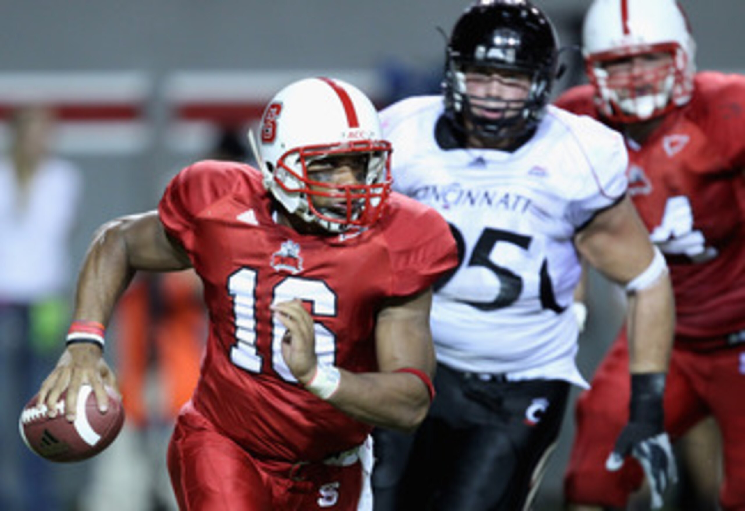 RALEIGH, NC - SEPTEMBER 16:  Derek Wolfe #95 of the Cincinnati Bearcats tries to chase down Russell Wilson #16 of the North Carolina State Wolfpack during their game at Carter-Finley Stadium on September 16, 2010 in Raleigh, North Carolina.  (Photo by Str