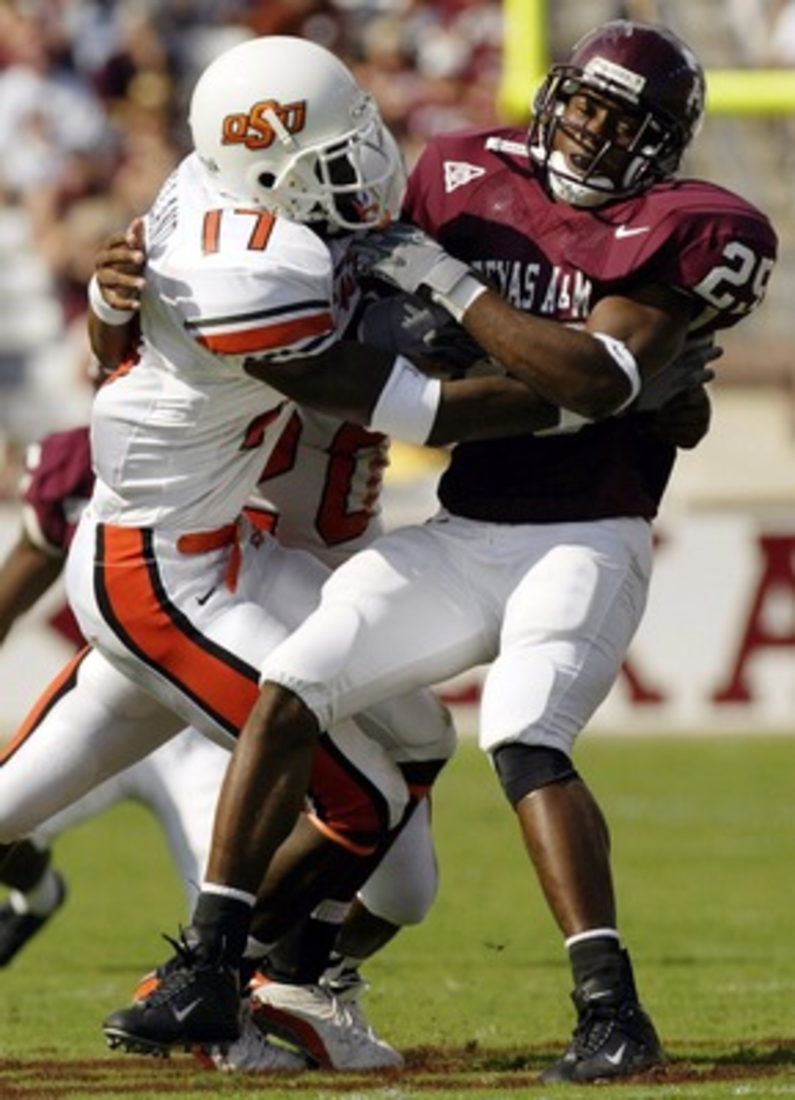COLLEGE STATION, TX - OCTOBER 25:  Running back Courtney Lewis #25 of the Texas A&M Aggies is tackled by Jon Holland #17 of the Oklahoma State Cowboys at Kyle Field on October 25, 2003 in College Station, Texas.  (Photo by Ronald Martinez/Getty Images)