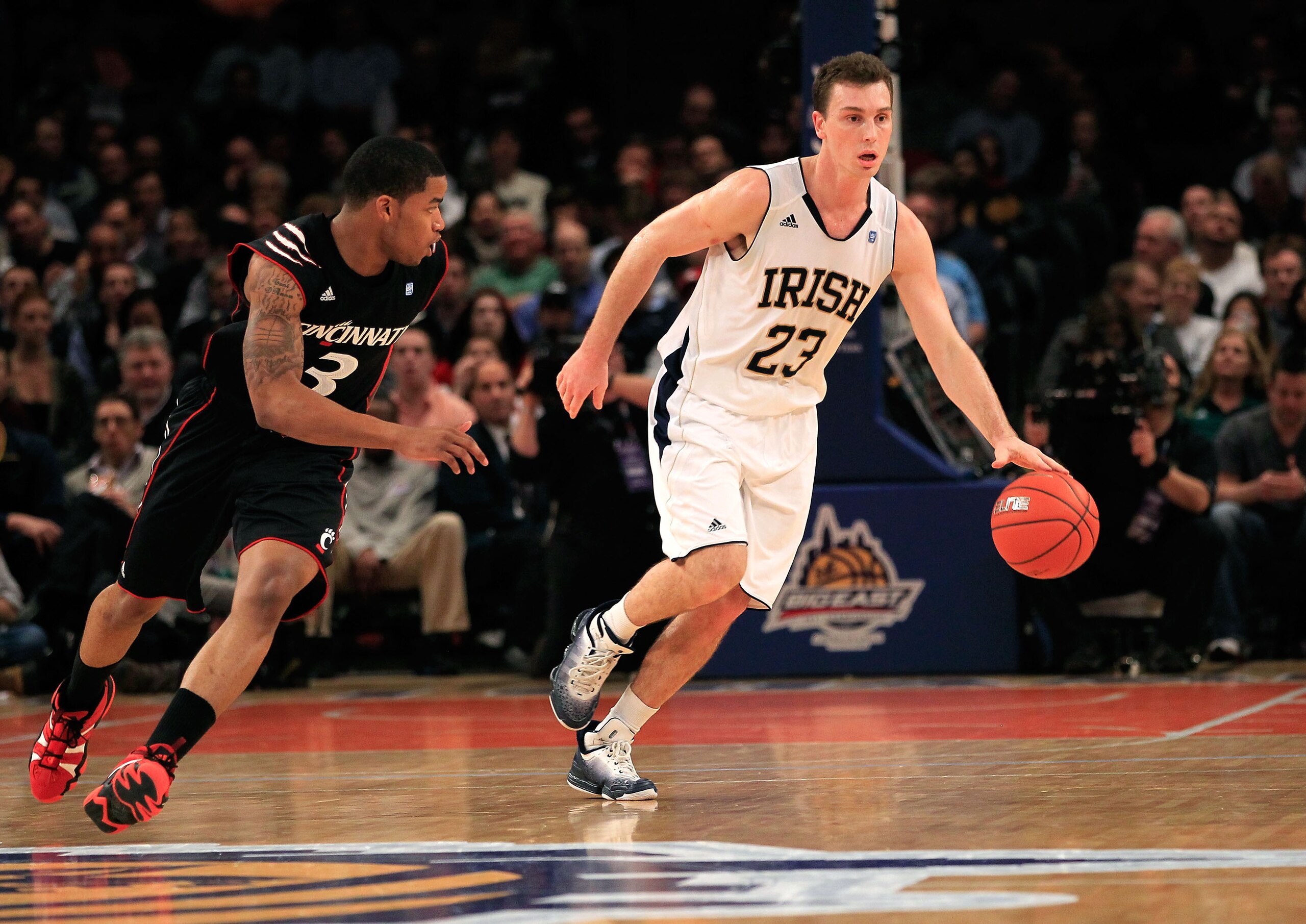 NEW YORK, NY - MARCH 10: Ben Hansbrough #23 of the Notre Dame Fighting Irish dribbles the ball up court against Dion Dixon #3 of the Cincinnati Bearcats during the quarterfinals of the 2011 Big East Men's Basketball Tournament presented by American Eagle