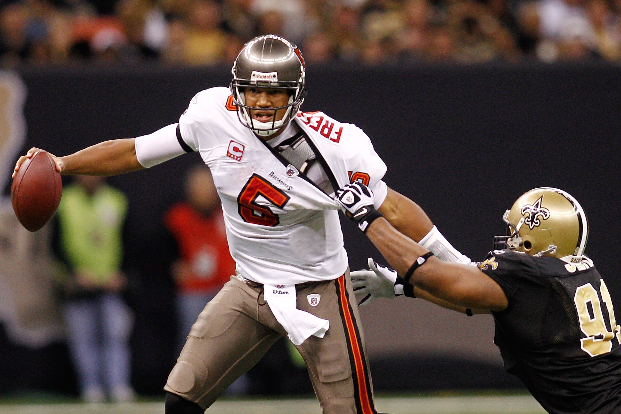 NEW ORLEANS, LA - JANUARY 02:  Quarterback Josh Freeman #5 of the Tampa Bay Buccaneers avoids a tackle by Will Smith #91 of the New Orleans Saints at the Louisiana Superdome on January 2, 2011 in New Orleans, Louisiana.   The Buccaneers defeated the Saint
