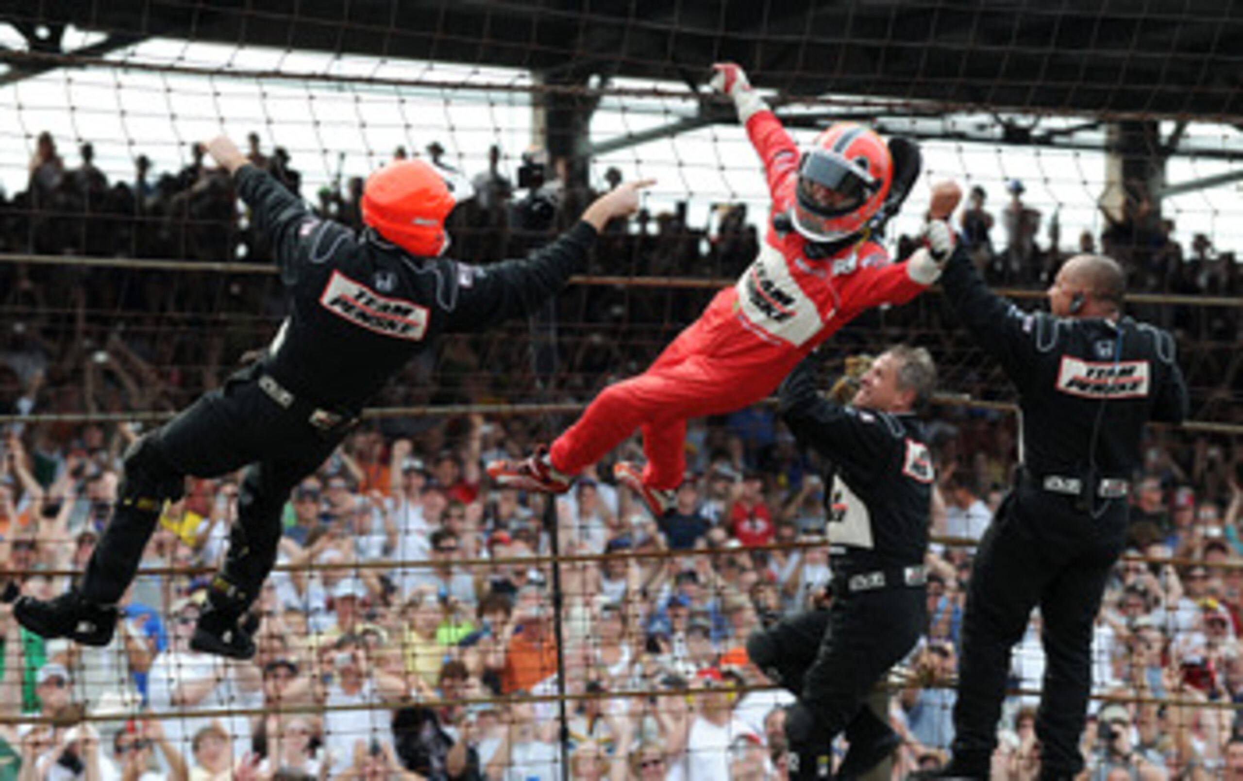 INDIANAPOLIS - MAY 24:  Helio Castroneves driver of the #3 Team Penske Dallara Honda climbs the front stretch fence with his teamates after winning the IRL IndyCar Series 93rd running of the Indianapolis 500 at the Indianapolis Motor Speedway on May 24, 2