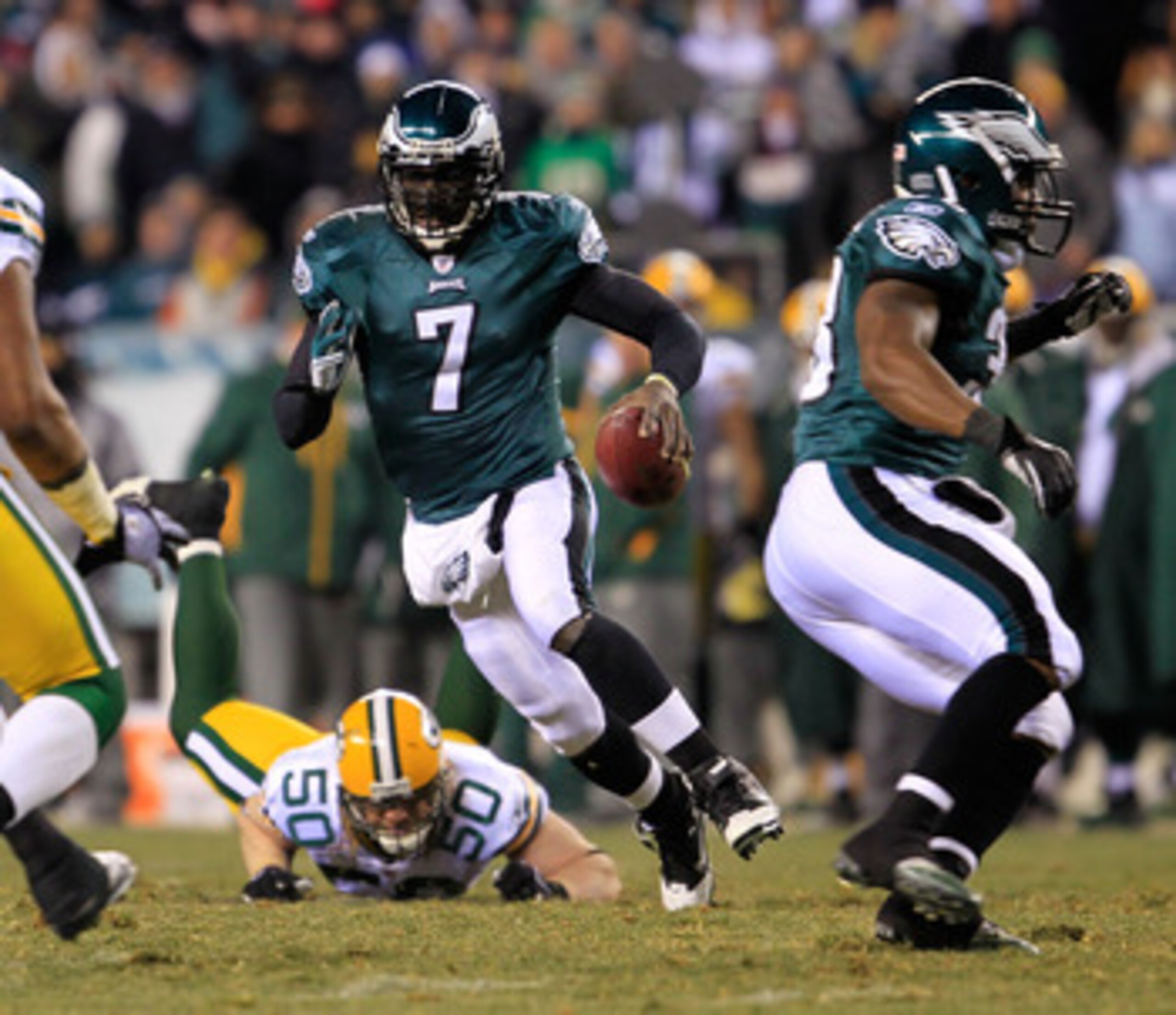 PHILADELPHIA, PA - JANUARY 09:  Michael Vick #7 of the Philadelphia Eagles scrambles against A.J. Hawk #50 and Desmond Bishop #55 of the Green Bay Packers during the 2011 NFC wild card playoff game at Lincoln Financial Field on January 9, 2011 in Philadel