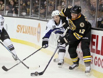 BOSTON, MA - MARCH 03:  Tomas Kaberle #12 of the Boston Bruins and Dominic Moore #19 of the Tampa Bay Lightning fight for the puck on March 3, 2011 at the TD Garden in Boston, Massachusetts.  (Photo by Elsa/Getty Images)