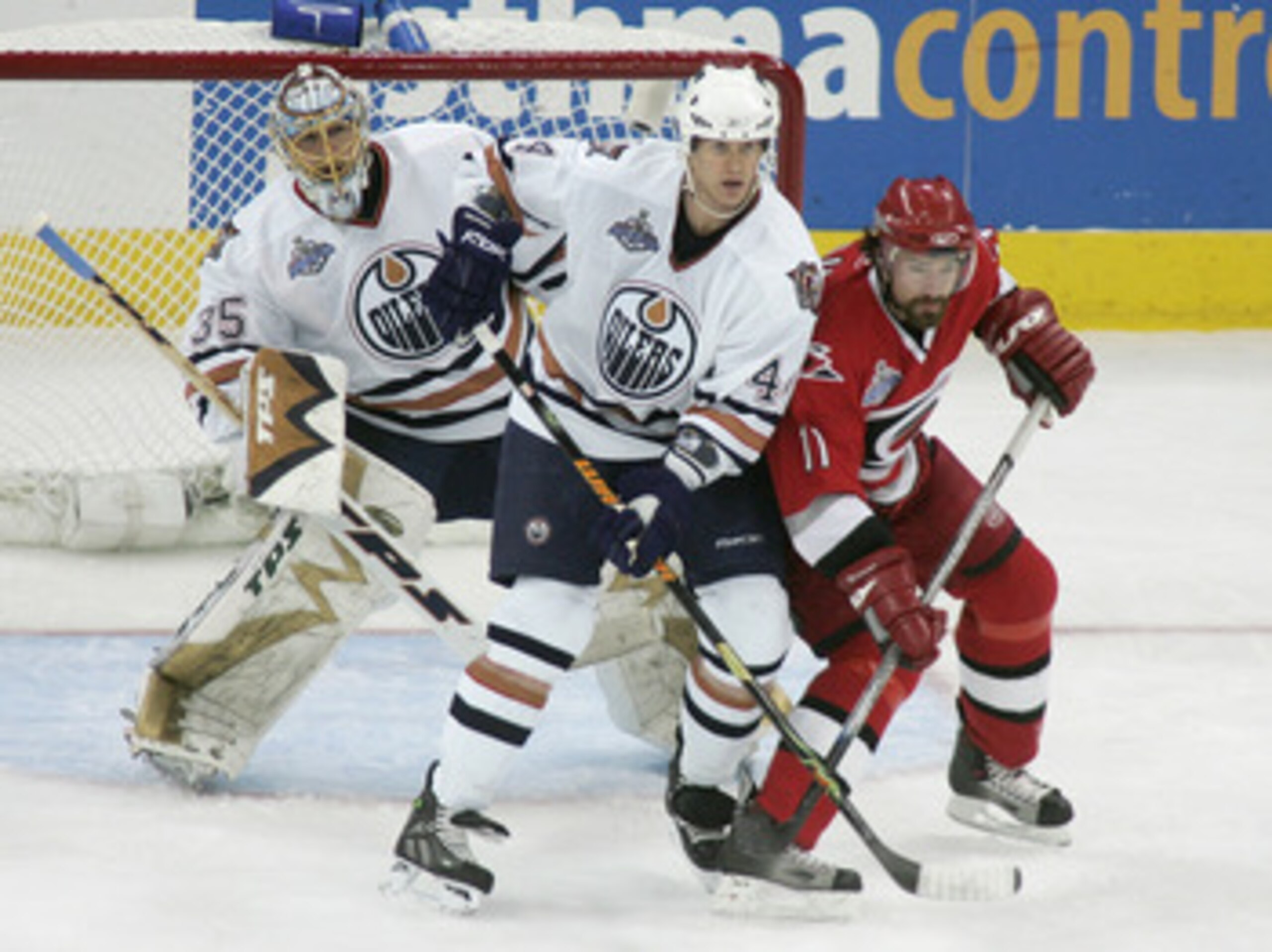 RALEIGH, NC - JUNE 5:  Chris Pronger #44 of the Edmonton Oilers vies for slot position with Justin Williams #11 of the Carolina Hurricanes as goaltender Dwayne Roloson #35 of the Edmonton Oilers tries to get a look at the play during game one of the 2006 