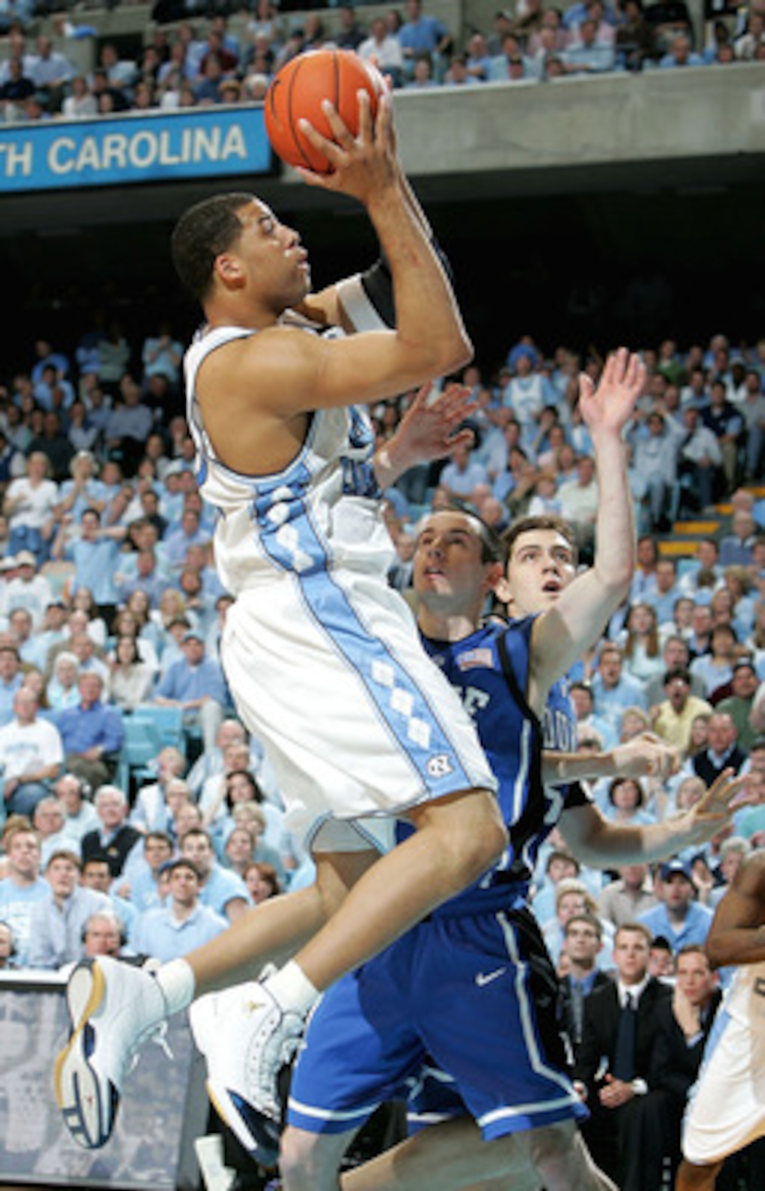 CHAPEL HILL, NC - MARCH 6:  J.J. Redick #4 of the Duke Blue Devils watches as Sean May #42 of the North Carolina Tar Heels goes to the basket on March 6, 2005 at the Dean E. Smith Center in Chapel Hill, North Carolina.  (Photo by Streeter Lecka/Getty Imag