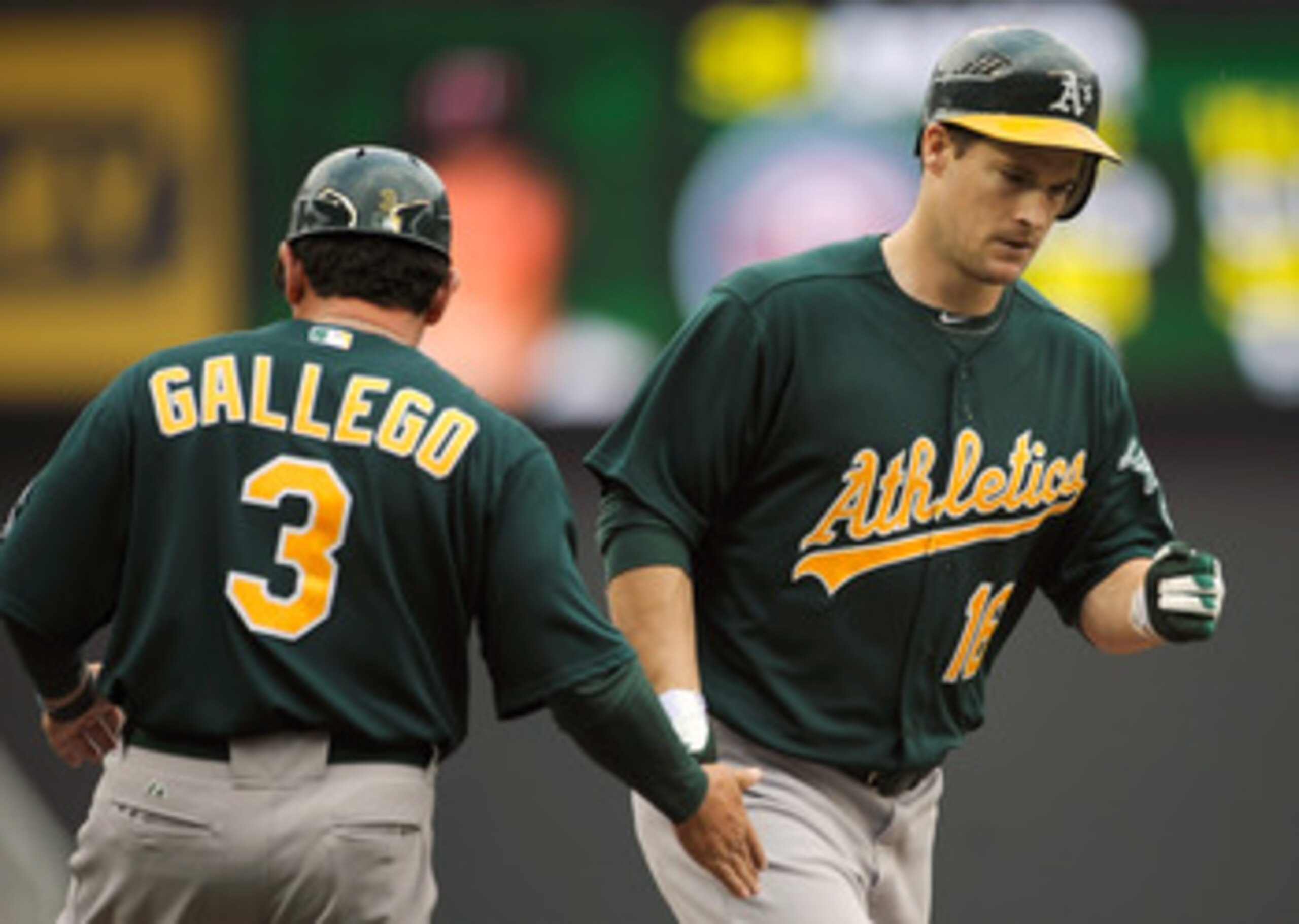 MINNEAPOLIS, MN - APRIL 10: Third base coach Mike Gallegro #3 of the Oakland Athletics congratulates Josh Willingham #16 as he rounds the bases following a solo home run off of Scott Baker #30 of the Minnesota Twins during the fourth inning of their game