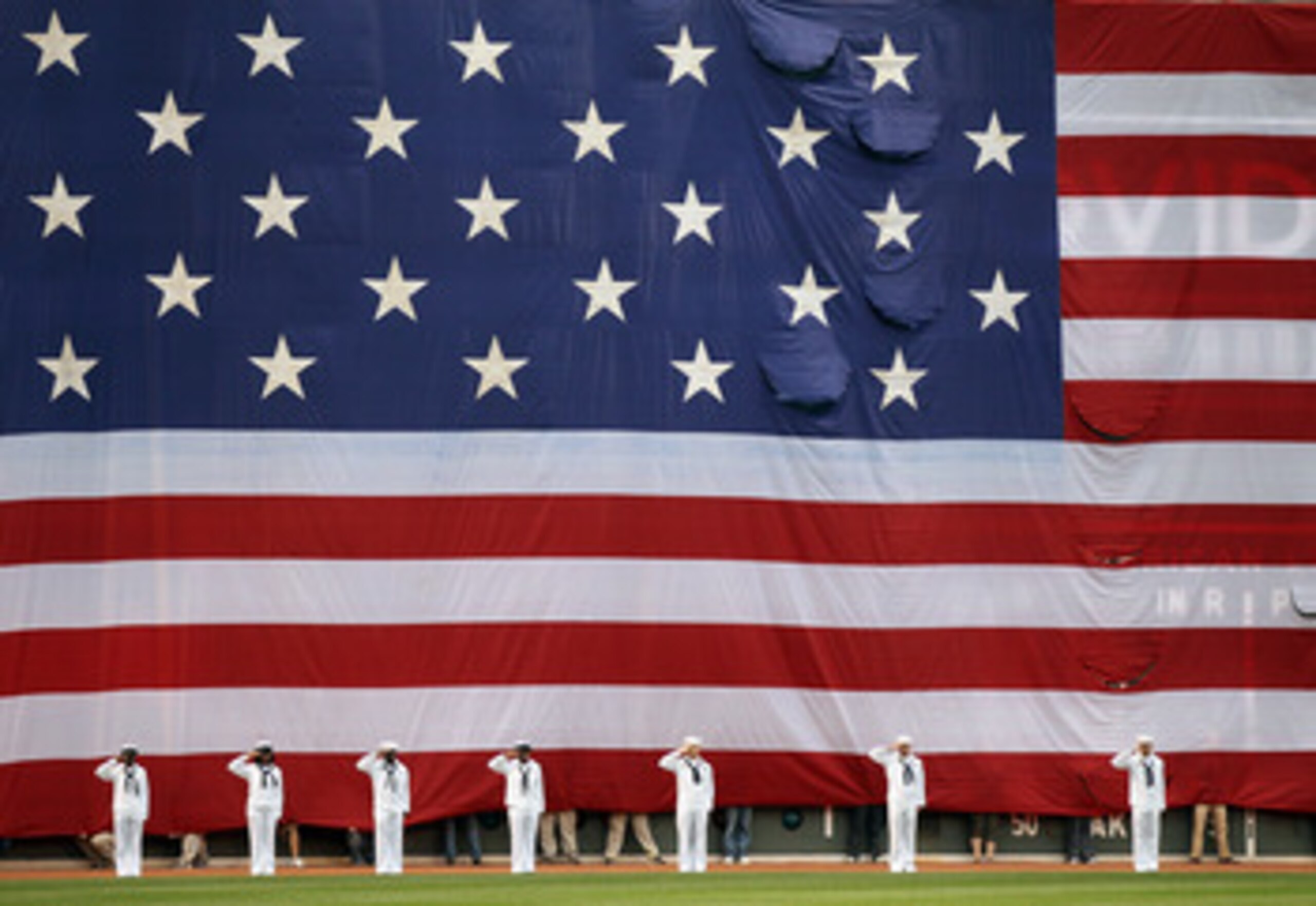 BOSTON, MA - MAY 02:  A giant flag covers the Green Monster as the national anthem is played before the game between the Boston Red Sox and the Los Angeles Angels on May 2, 2011 at Fenway Park in Boston, Massachusetts.  Both teams lined up on the baseline