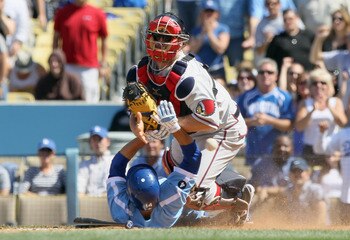 LOS ANGELES, CA - APRIL 21:  Catcher Brian McCann #16 of the Atlanta Braves drops the ball as Jamey Carroll #14 of the Los Angeles Dodgers slides safely into home to tie the game in the ninth inning at Dodger Stadium on April 21, 2011 in Los Angeles, Cali