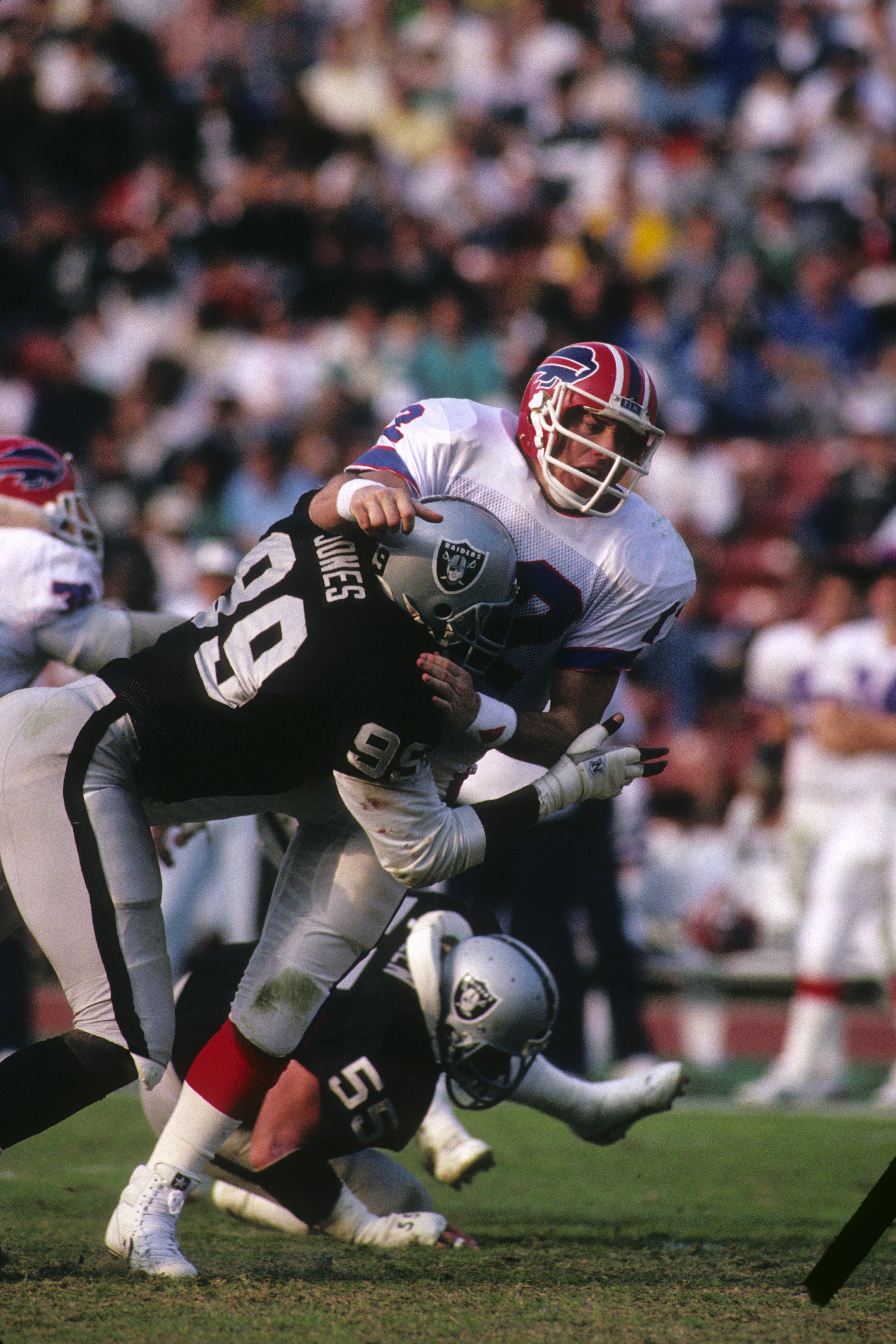 LOS ANGELES - DECEMBER 6:  Defensive end Sean Jones #99 of Los Angeles Raiders tackles Buffalo Bills quarterback Jim Kelly #12 during the game at the Los Angeles Memorial Coliseum on December 6, 1987 in Los Angeles, California.  The Raiders won 34-21. (Ph