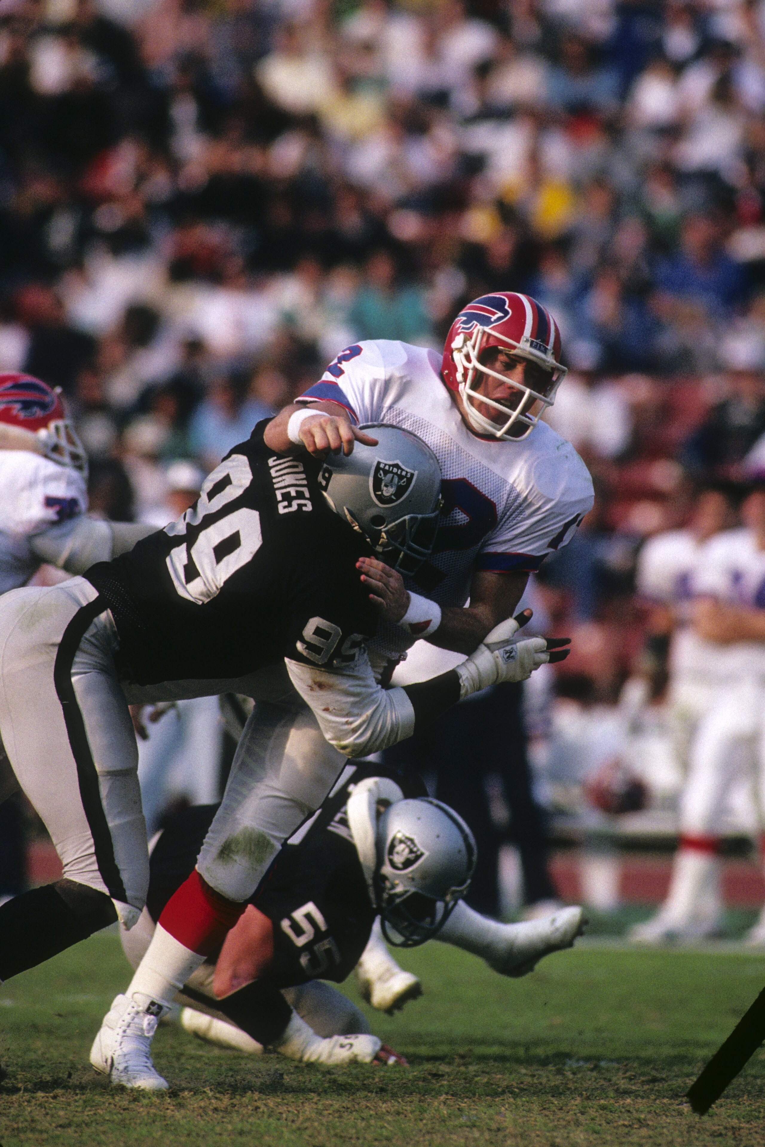 LOS ANGELES - DECEMBER 6: Defensive end Sean Jones #99 of Los Angeles Raiders tackles Buffalo Bills quarterback Jim Kelly #12 during the game at the Los Angeles Memorial Coliseum on December 6, 1987 in Los Angeles, California. The Raiders won 34-21. (Ph LOS ANGELES - DECEMBER 6: Defensive end Sean Jones #99 of Los Angeles Raiders tackles Buffalo Bills quarterback Jim Kelly #12 during the game at the Los Angeles Memorial Coliseum on December 6, 1987 in Los Angeles, California. The Raiders won 34-21. (Ph