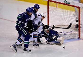 VANCOUVER, CANADA - MAY 15:  Ryan Kesler #17 and Dan Hamhuis #2 of the Vancouver Canucks defend Joe Thornton #19 of the San Jose Sharks goaltender Roberto Luongo #1 makes a save in the third period in the second period in Game One of the Western Conferenc