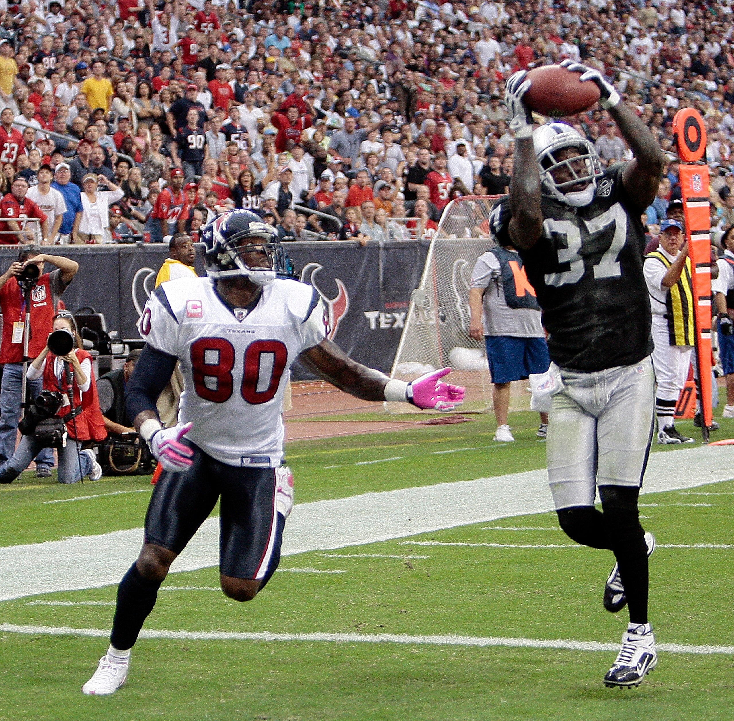 HOUSTON - OCTOBER 04:  Cornerback Chris Johnson #37 of the Oakland Raiders intercepts a pass intended for wide receiver Andre Johnson #80 of the Houston Texans in the first half at Reliant Stadium on October 4, 2009 in Houston, Texas.  (Photo by Bob Levey