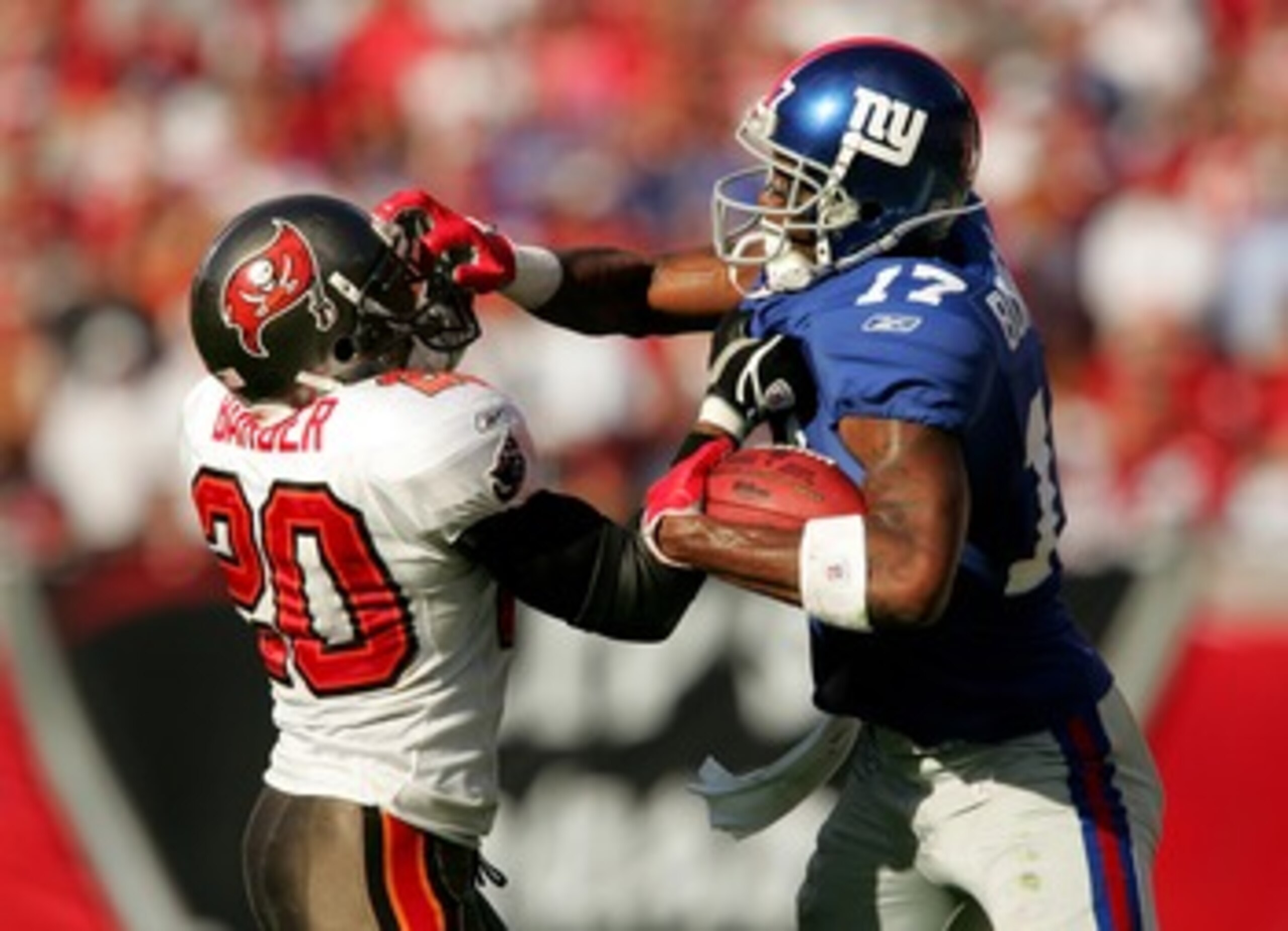 TAMPA, FL - JANUARY 06:  Plaxico Burress #17 of the New York Giants grabs the face mask of Ronde Barber #20 of the Tampa Bay Buccaneers in the fourth quarter of the NFC Wild Card game against Tampa Bay Buccaneers at Raymond James Stadium on January 6, 200