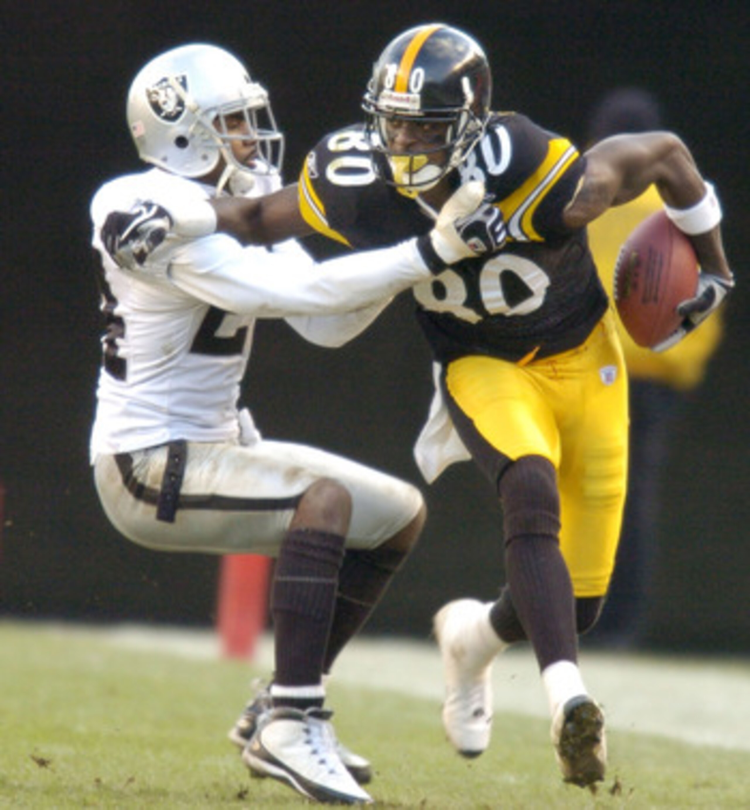 PITTSBURGH - DECEMBER 7:  Plaxico Burress #80 of the Pittsburgh Steelers is tackled by Charles Woodson #24 of the Oakland Raiders duirng the third quarter on December 7, 2003 at Heinz Field in Pittsburgh, Pennsylvania. The Steelers defeated the Raiders 27