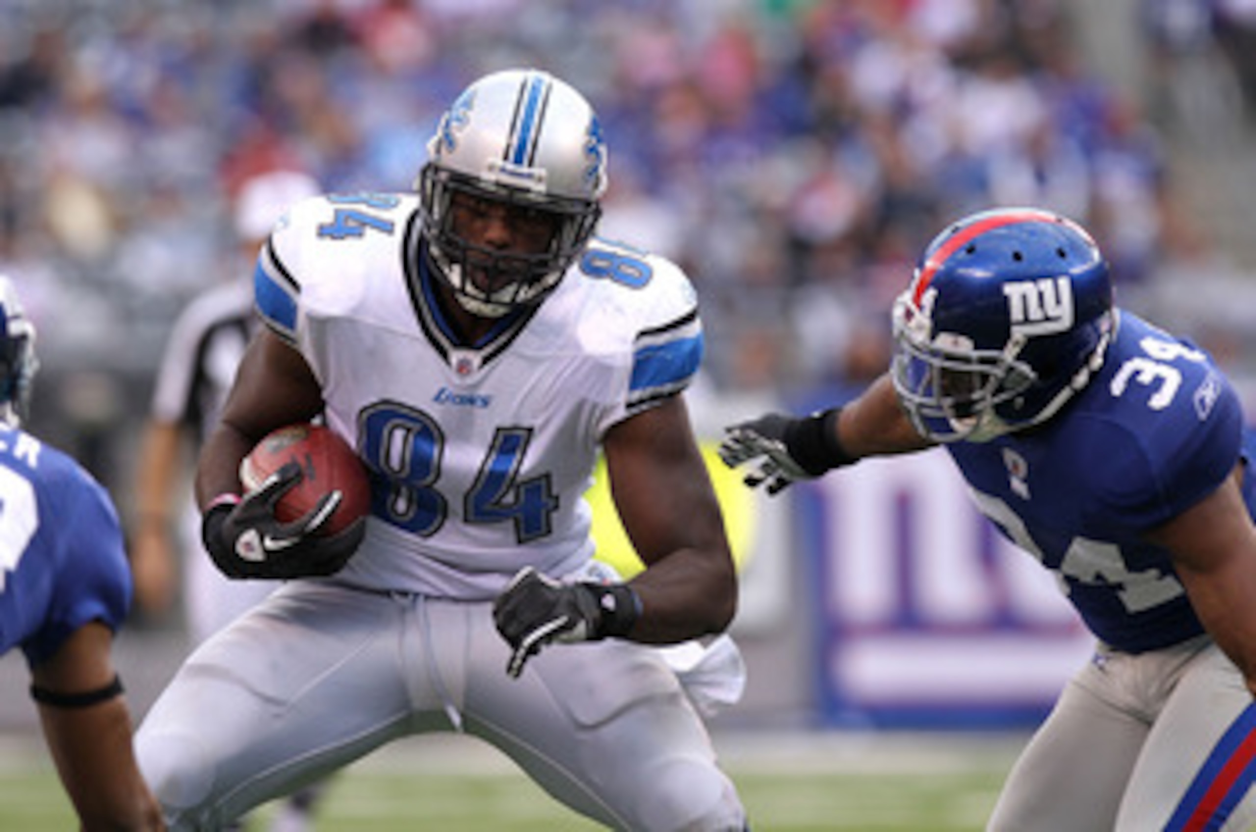 EAST RUTHERFORD, NJ - OCTOBER 17: Brandon Pettigrew #84 of the Detroit Lions runs with the ball under pressure from Deon Grant #34 of the New York Giants at New Meadowlands Stadium on October 17, 2010 in East Rutherford, New Jersey.  (Photo by Nick Laham/