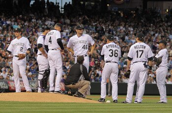 DENVER, CO - MAY 10:  Assistant trainer Scott Gehret attends to starting pitcher Jason Hammel #46 of the Colorado Rockies after he was hit in the leg by a line drive by Ronny Paulino #9 of the New York Mets in the fourth inning at Coors Field on May 10, 2
