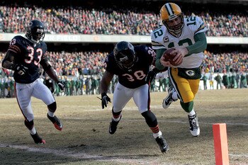 CHICAGO, IL - JANUARY 23:  Quarterback Aaron Rodgers #12 of the Green Bay Packers dives into the corner of the endzone for a one-yard touchdown run against Danieal Manning #38 of the Chicago Bears in the first quarter of the NFC Championship Game at Soldi