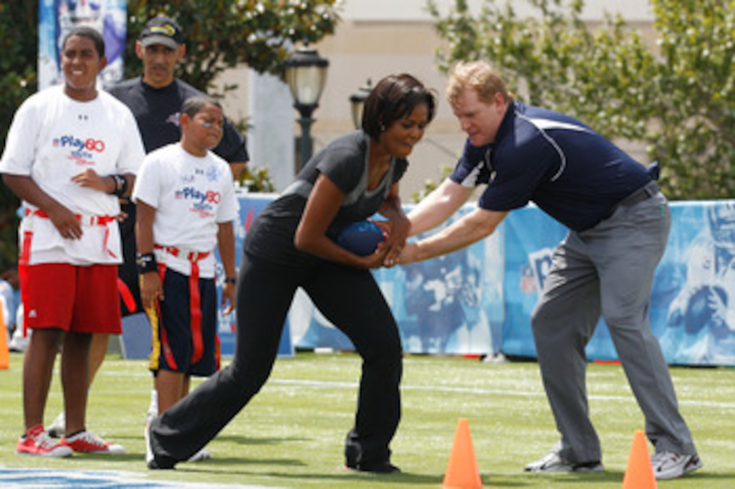 NEW ORLEANS - SEPTEMBER 08:  U.S. first lady Michelle Obama gets the football during a drill from  NFL commissioner Roger Goodell  during the NFLï¿½s Play 60 campaign to fight childhood obesity at Brock Elementary School September 8, 2010 in New Orleans, Lo