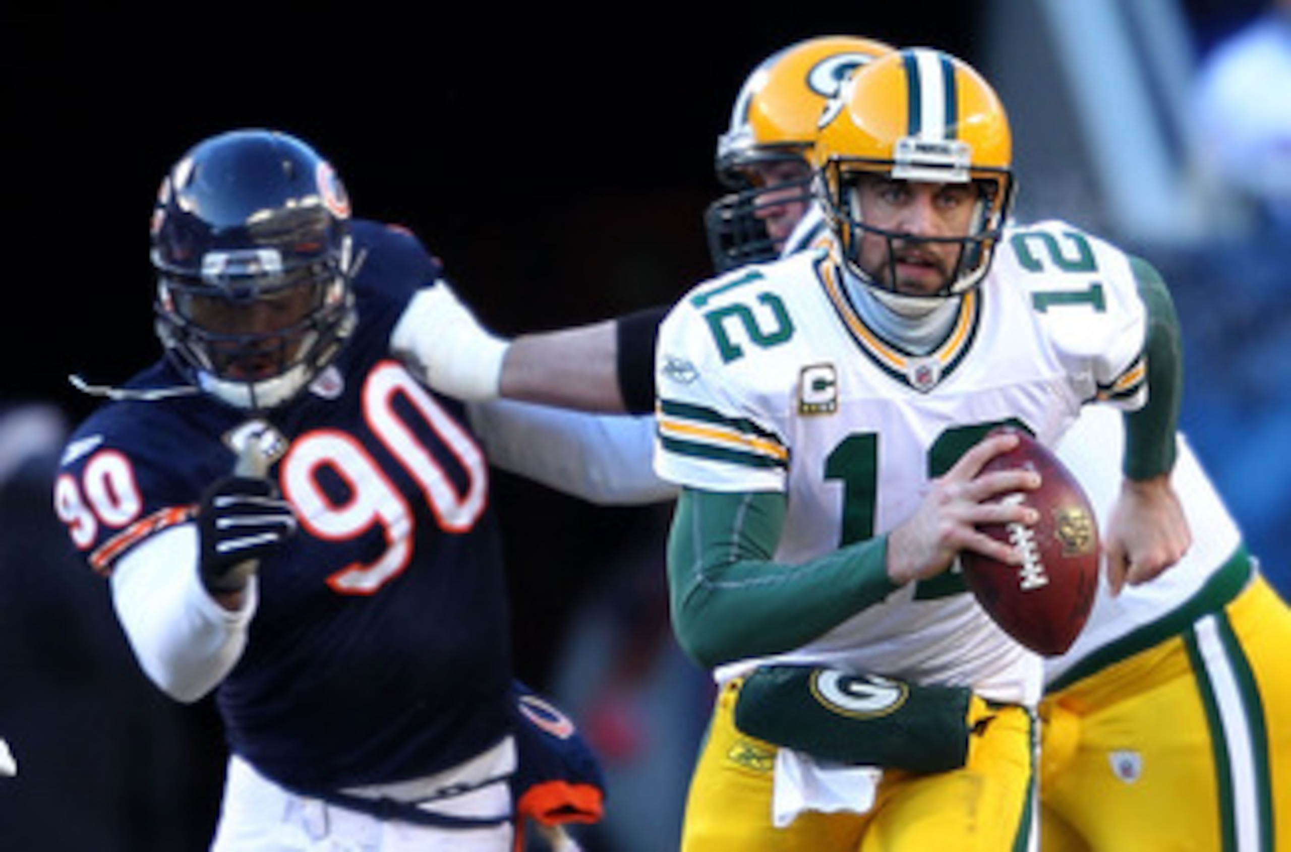 CHICAGO, IL - JANUARY 23:  Quarterback Aaron Rodgers #12 of the Green Bay Packers runs the ball ahead of Julius Peppers #90 of the Chicago Bears in the NFC Championship Game at Soldier Field on January 23, 2011 in Chicago, Illinois.  (Photo by Andy Lyons/