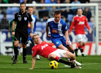 WIGAN, ENGLAND - FEBRUARY 26:  James McCarthy of Wigan Athletic competes with Paul Scholes of Manchester United during the Barclays Premier League match between Wigan Athletic and Manchester United at the DW Stadium on February 26, 2011 in Wigan, England.