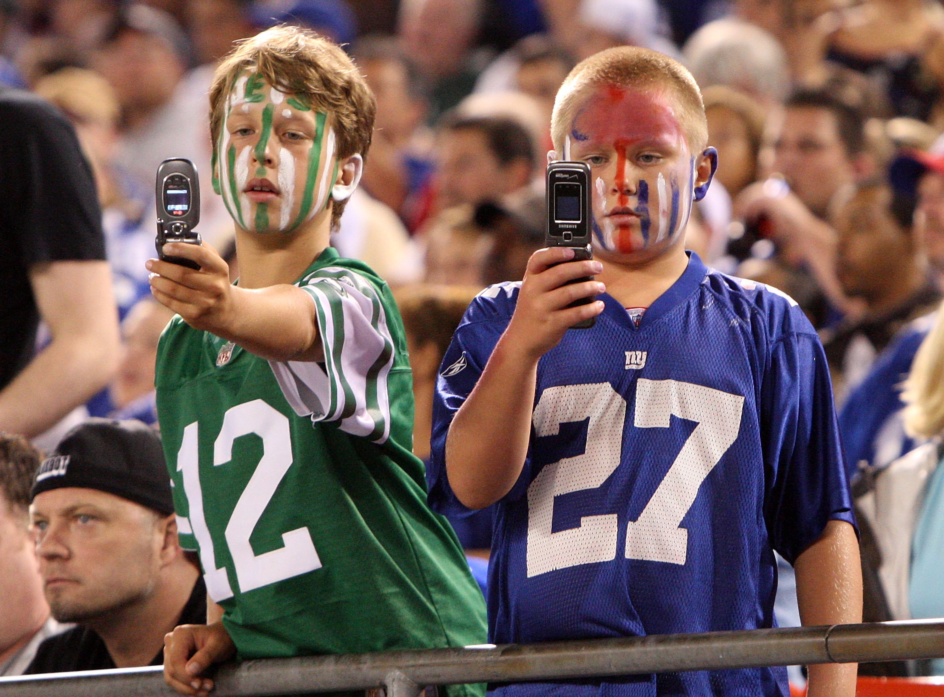 EAST RUTHERFORD, NJ - AUGUST 29:  Young fans of the New York Giants and the New York Jets take photographs during a pre season game on August 29, 2009 at Giants Stadium in East Rutherford, New Jersey.  (Photo by Jim McIsaac/Getty Images)